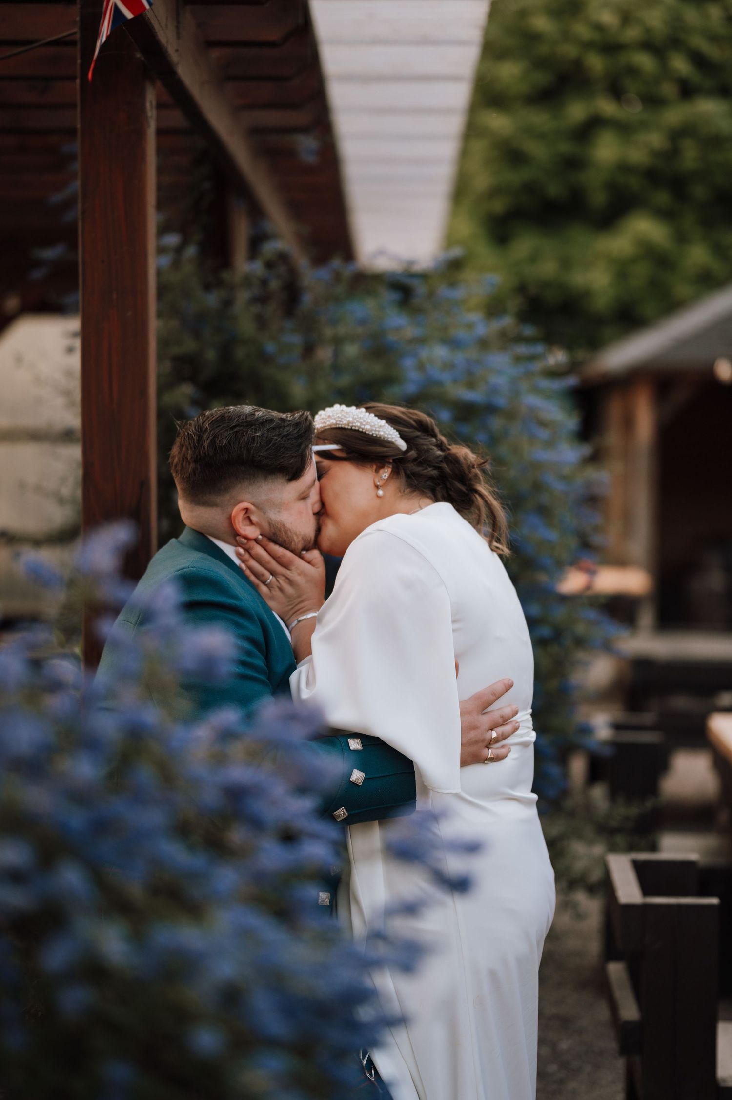 Romantic wedding couple shares intimate kiss under garden pergola.