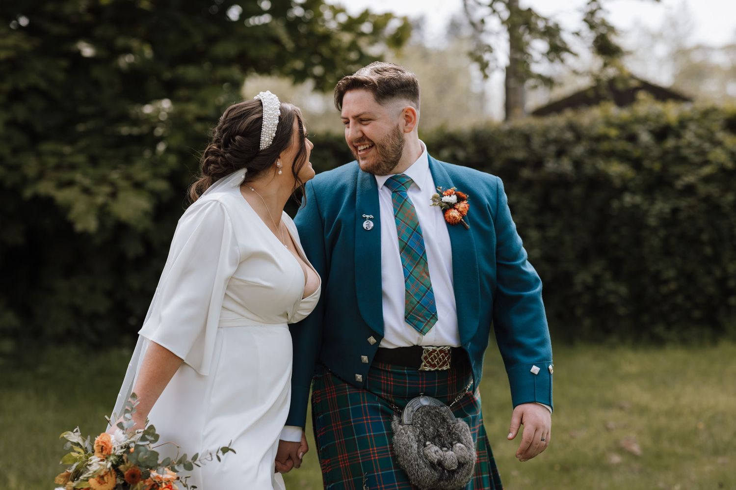 Wedding couple in white dress and traditional Scottish kilt sharing an intimate moment.