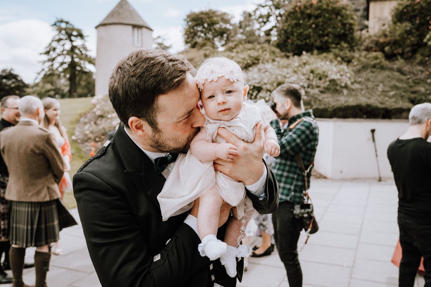 Tender moment between adult and baby at outdoor formal event.