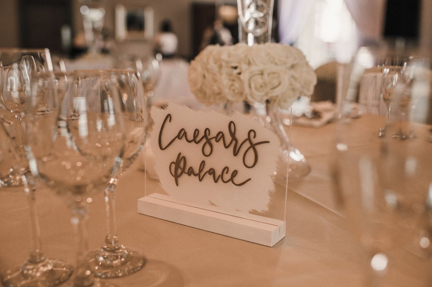 Elegant wedding table place card holder displaying cursive text at a formal reception setting.