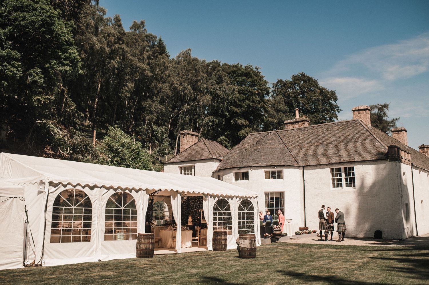 White wedding venue with outdoor tent and classic architecture in natural setting.
