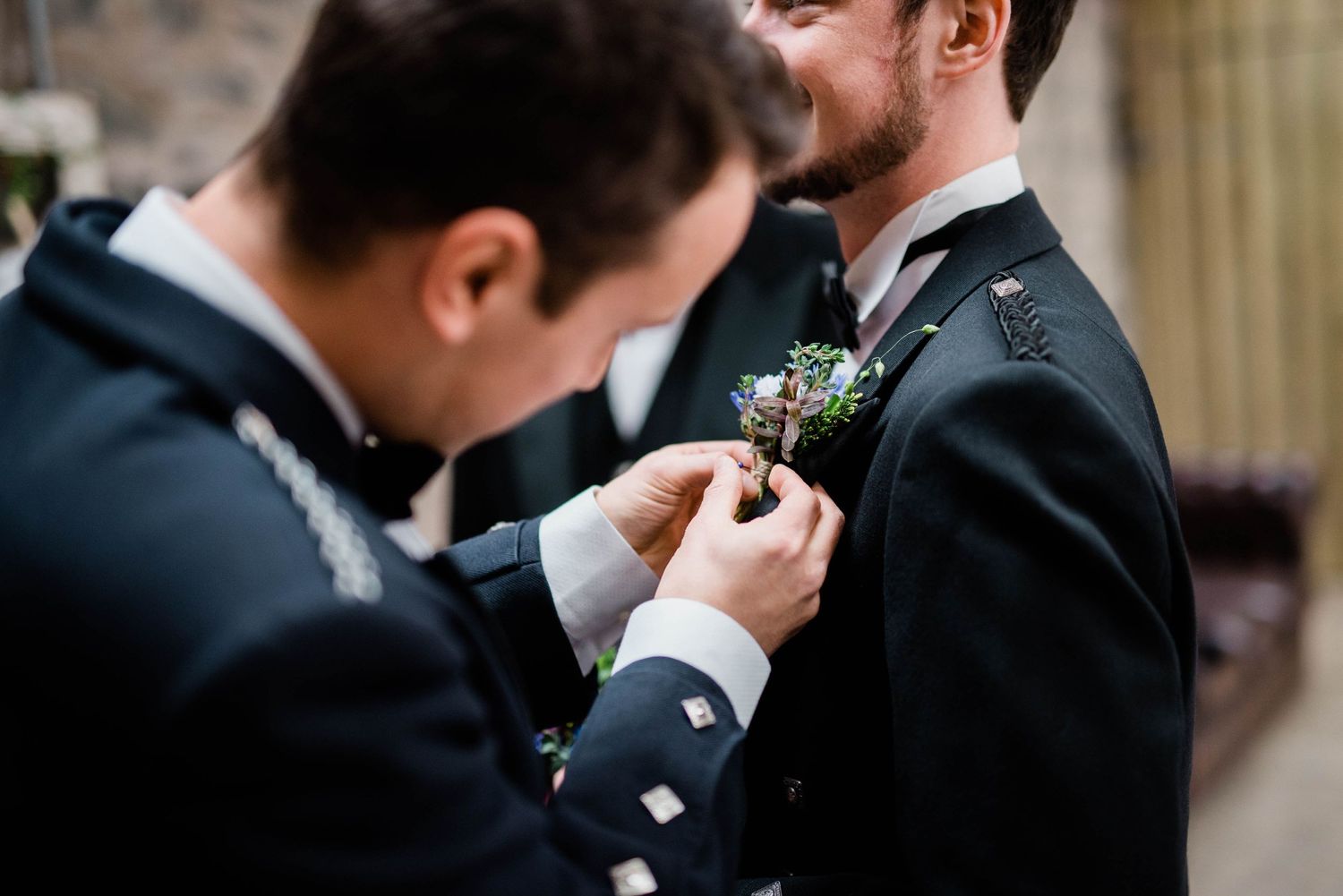 Close-up shot of a kilt pin being adjusted on traditional Scottish formal wear.