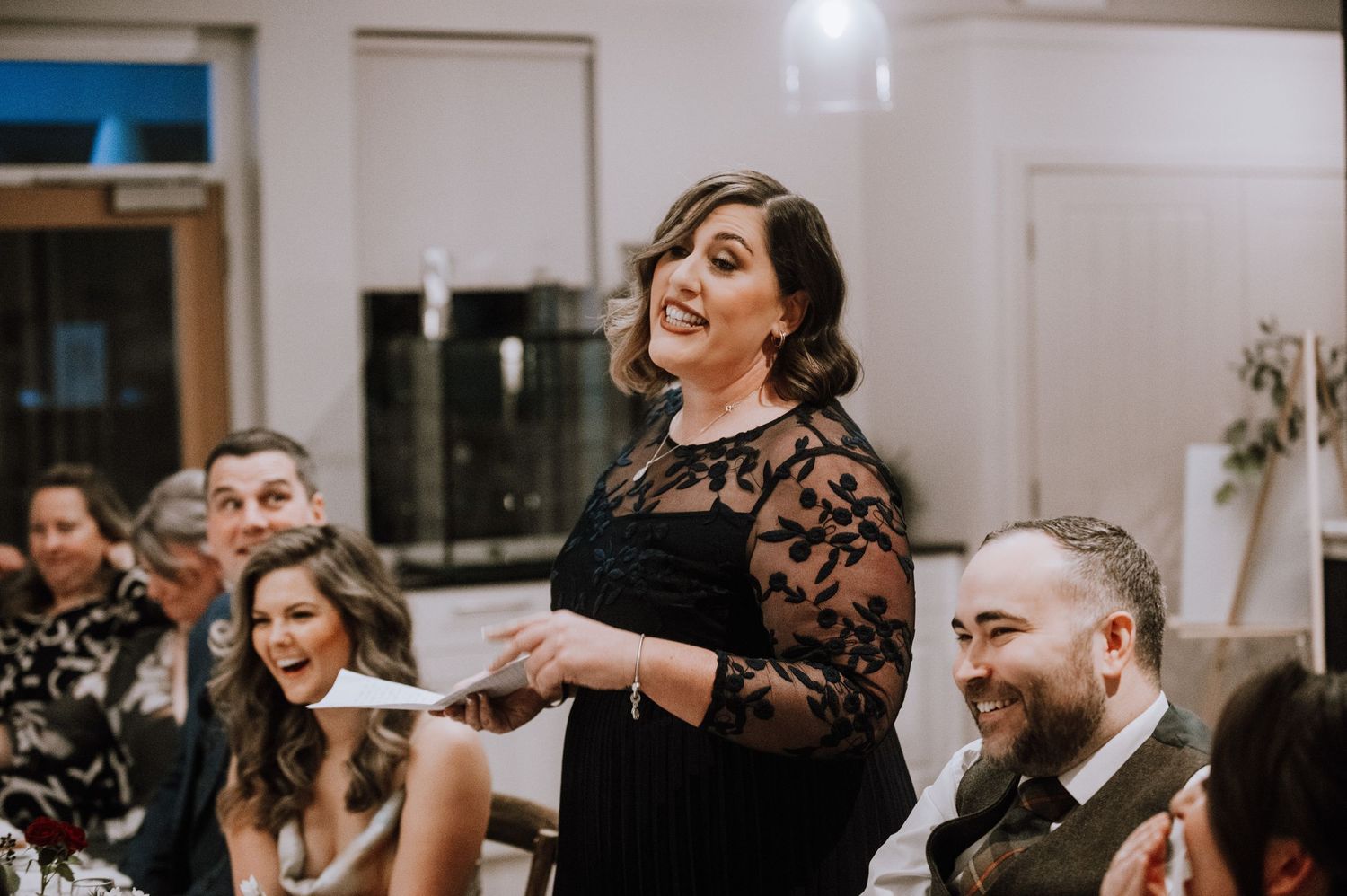 Same Sex Wedding Photography. Wedding guests laugh and celebrate during an indoor reception dinner.
