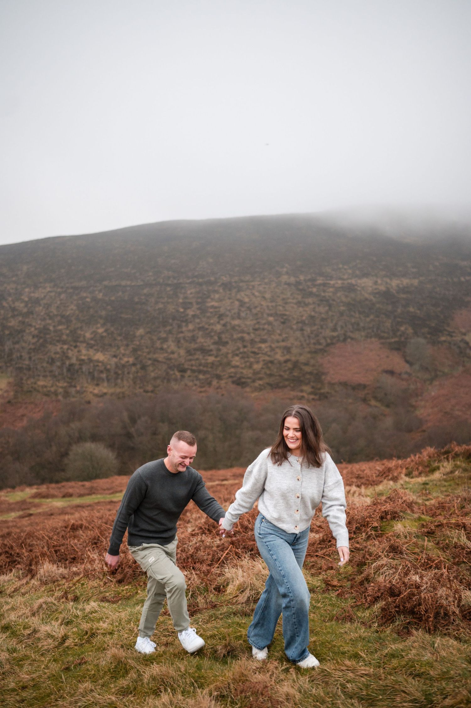 Engagement photography session Aberdeen. People playfully interact on a misty hillside covered in autumn heather.