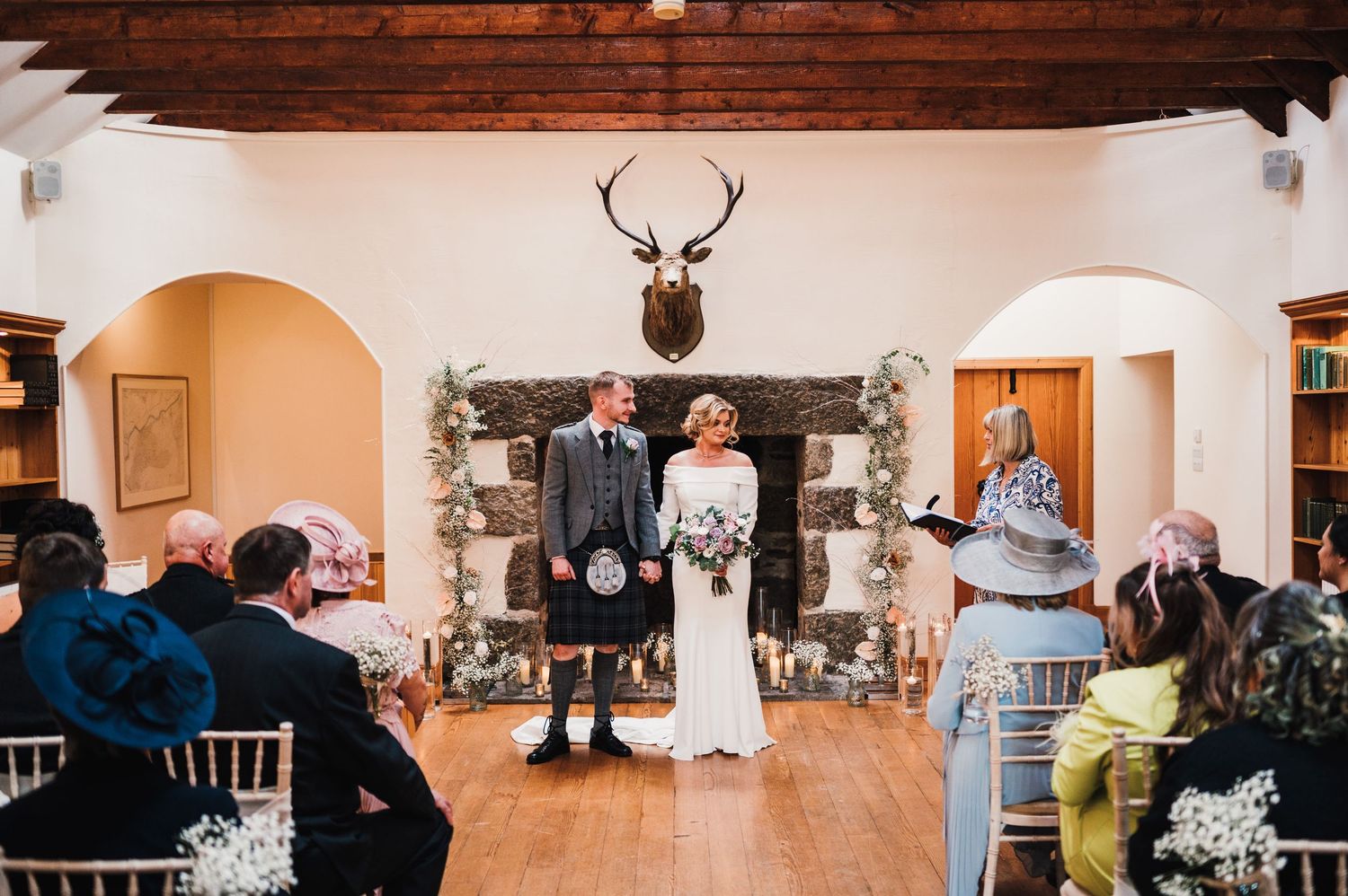 Large reception hall with wooden beams and elegant decor set up for a wedding celebration.
