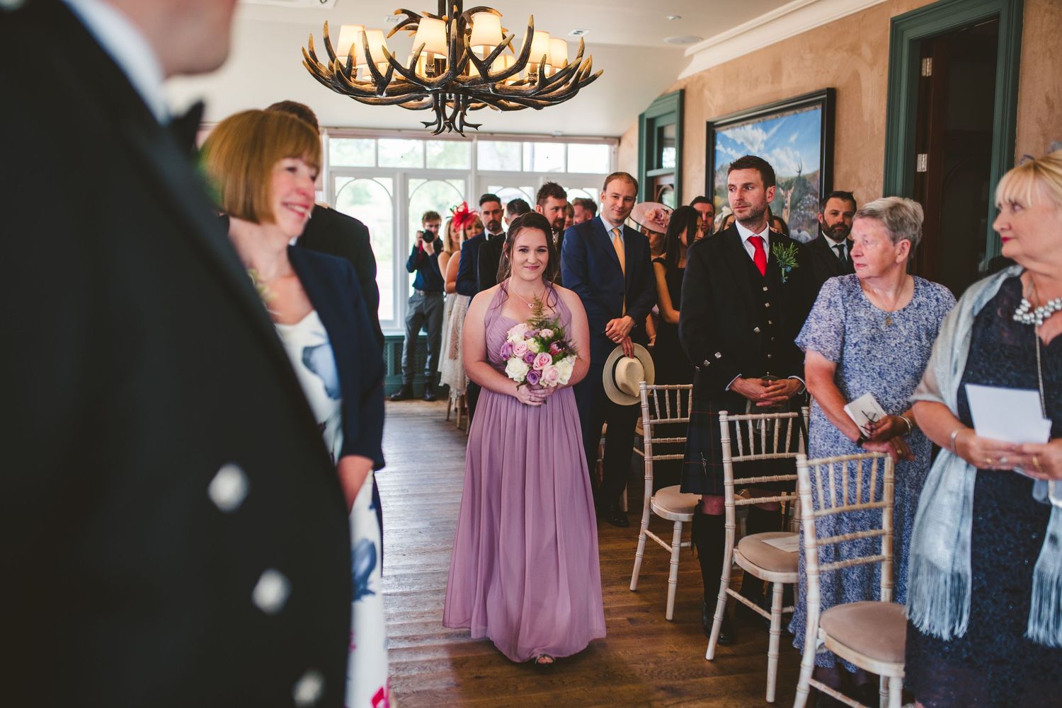 Wedding celebration in an elegant venue with guests seated at round tables.