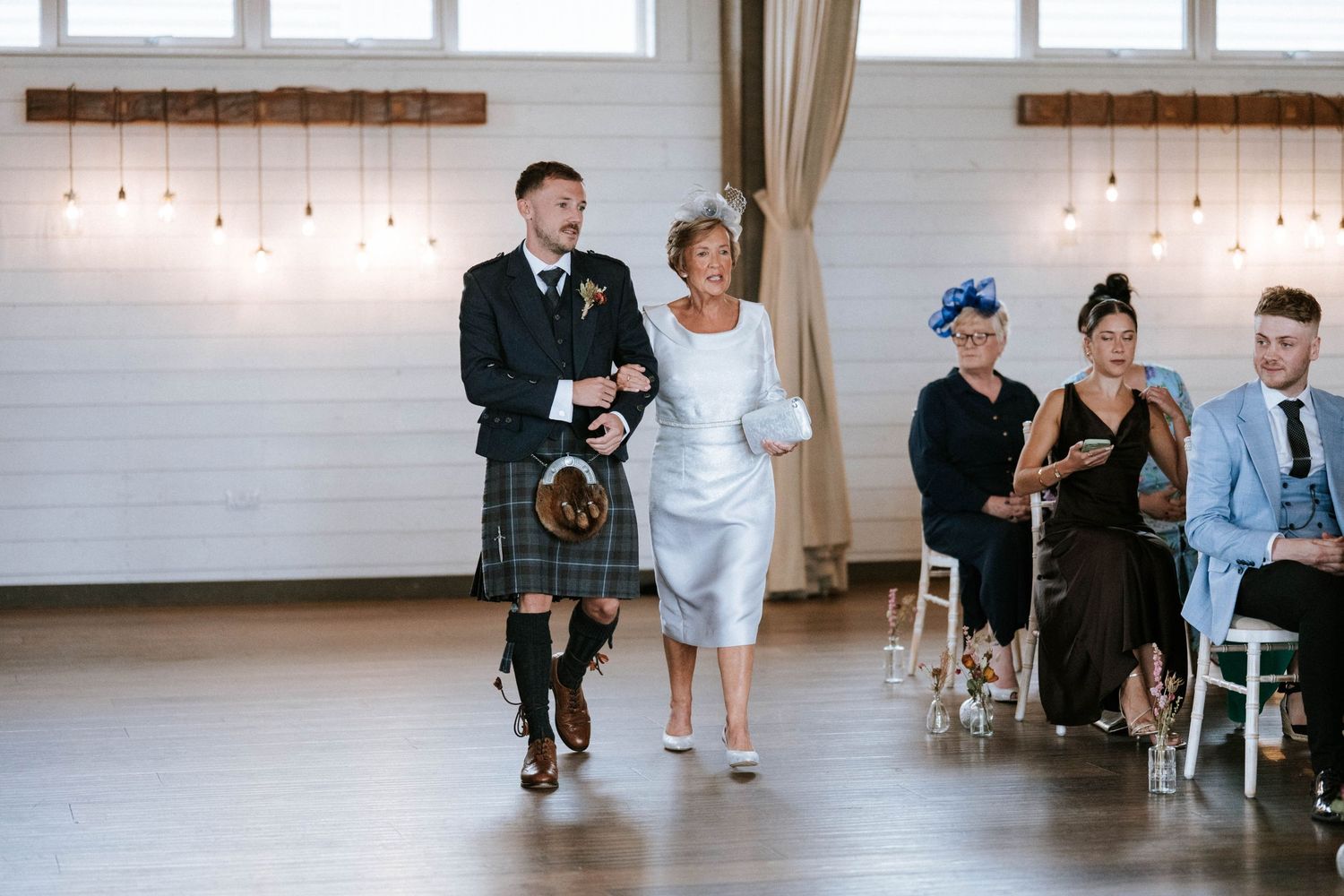 Wedding reception in a bright modern venue with string lights and white decor.