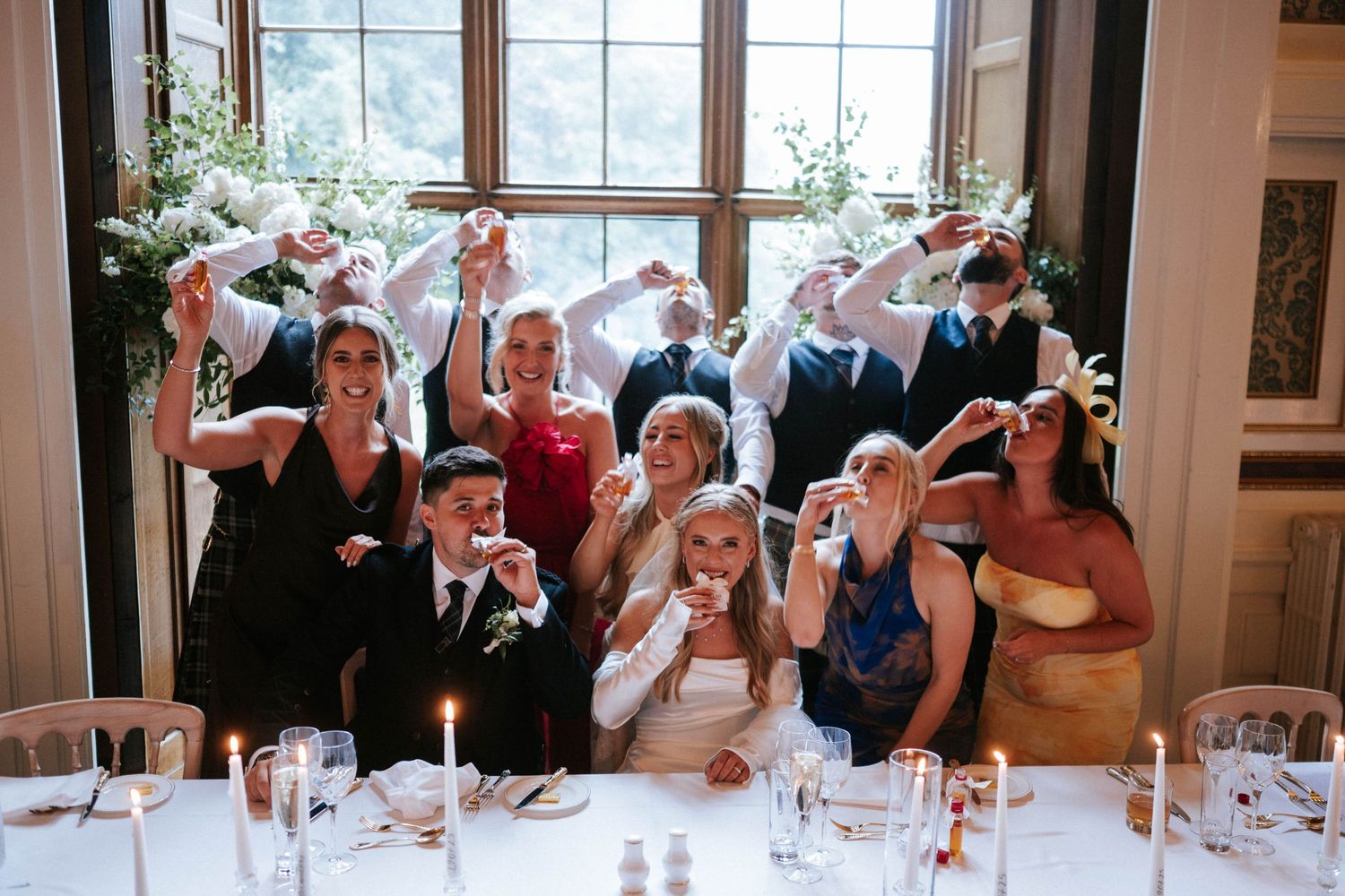 Wedding guests raising their glasses in celebration at a formal dining table.