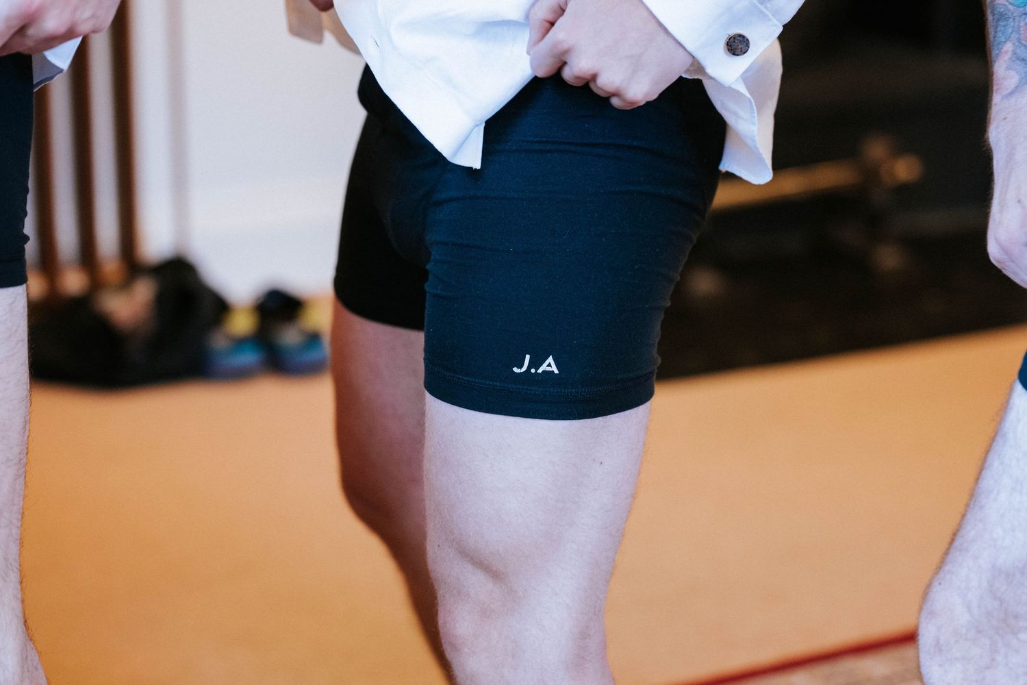 Close-up view of black athletic shorts with initials J.A. embroidered on the side.