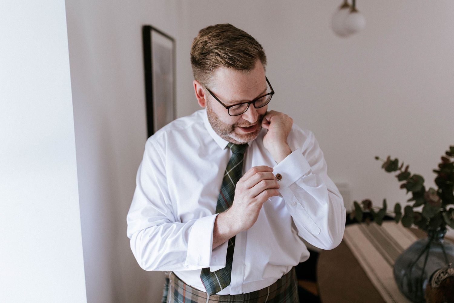 Person in white shirt and tie sitting at desk in contemplative pose.