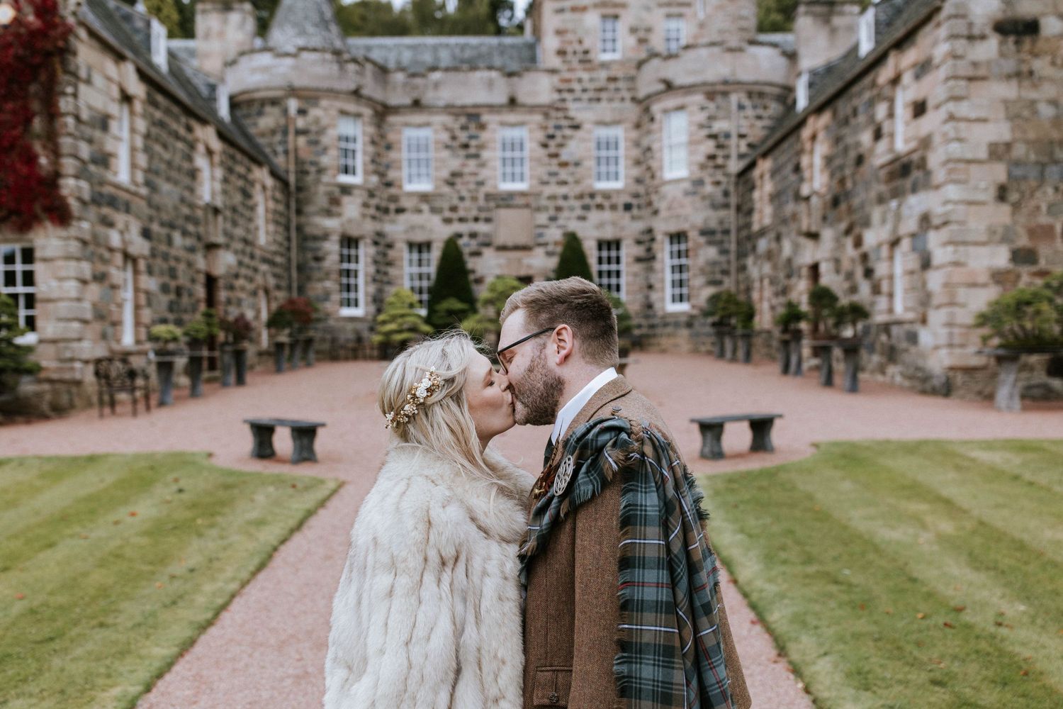 Romantic moment between newlyweds in front of historic Scottish castle.