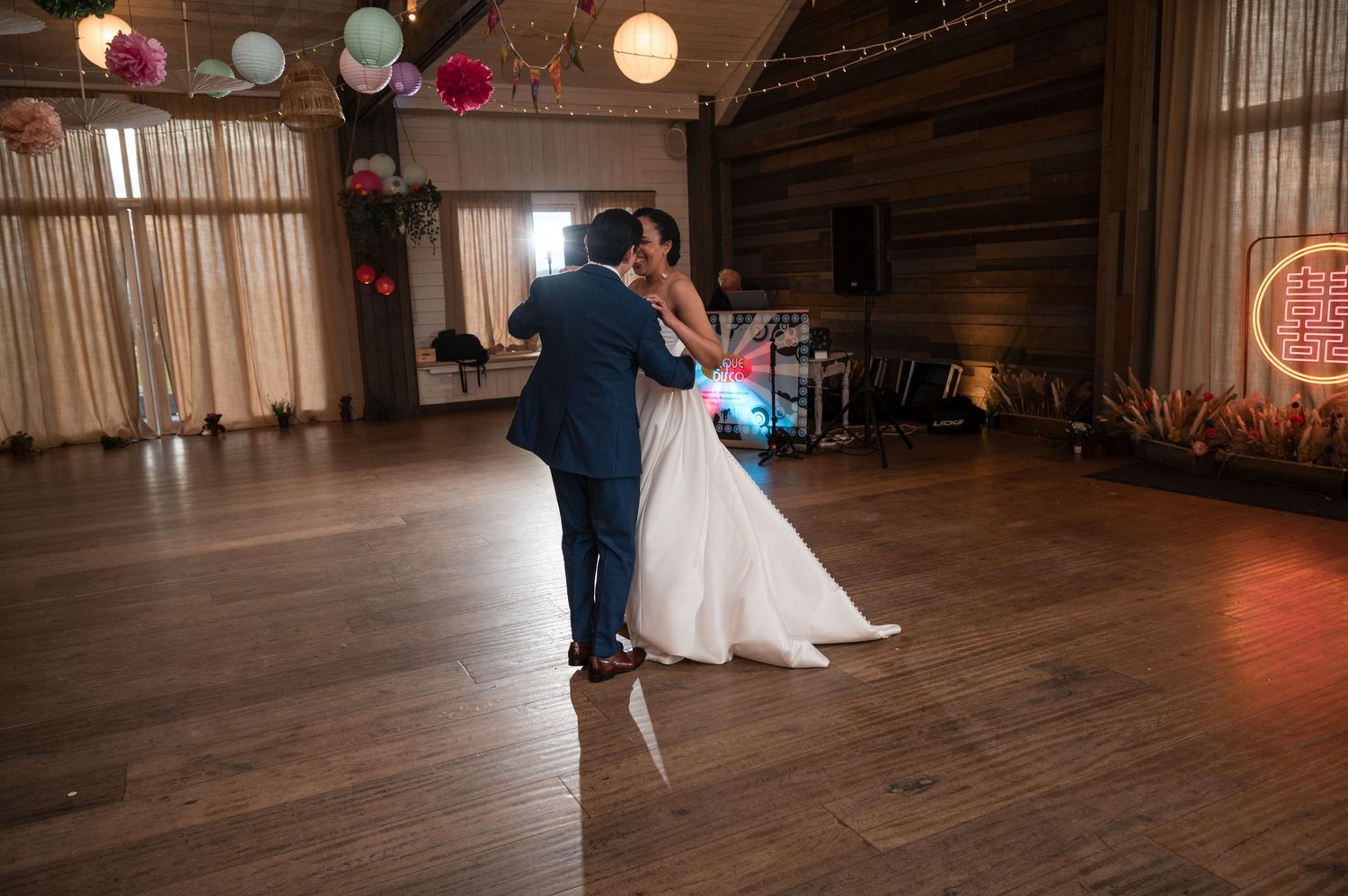 First dance in rustic barn venue with warm lighting and wooden floors.