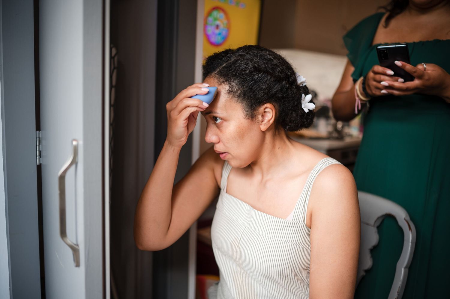 A person in a white top getting ready in front of a mirror.