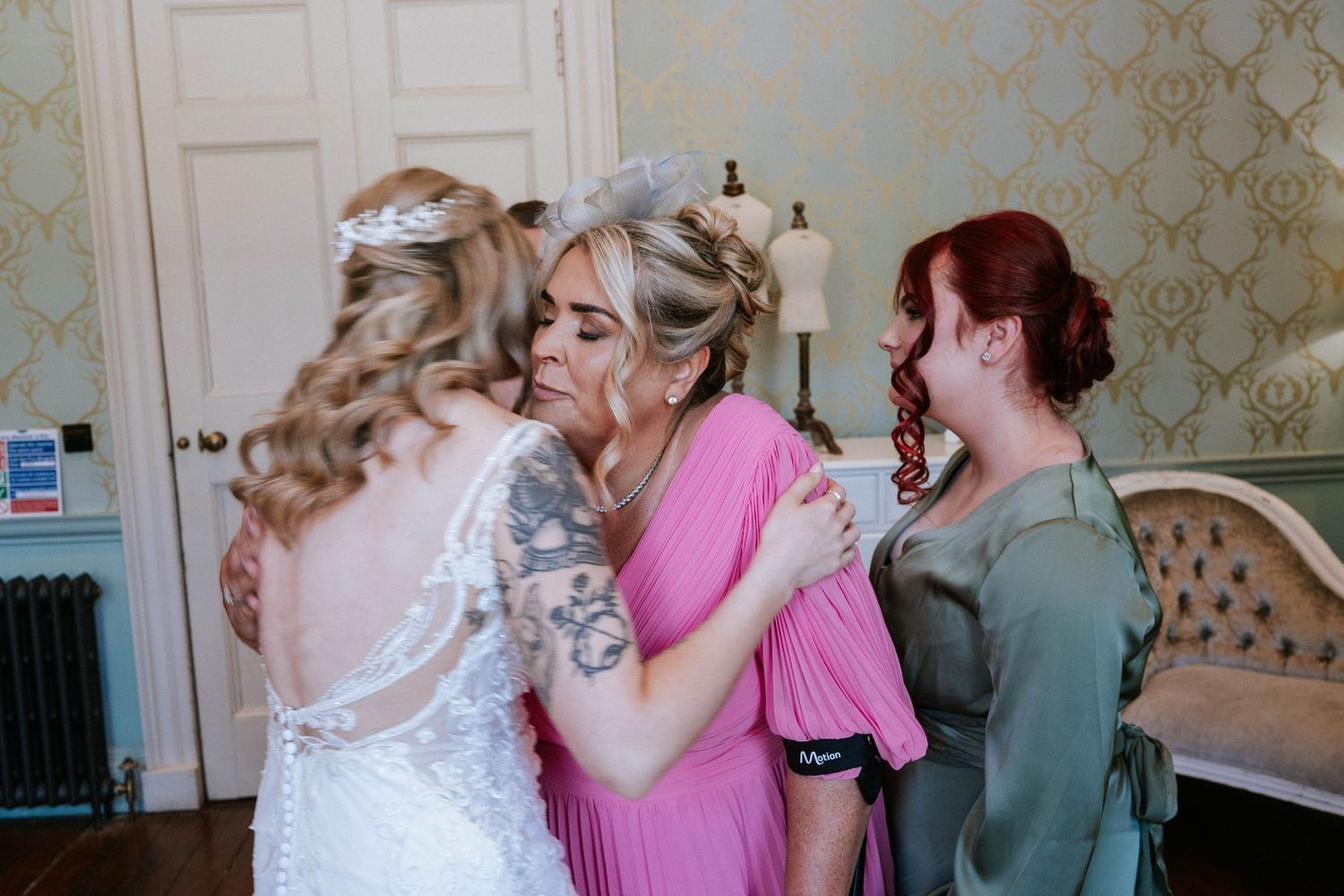 Emotional moment shared between wedding party members in pastel dresses.