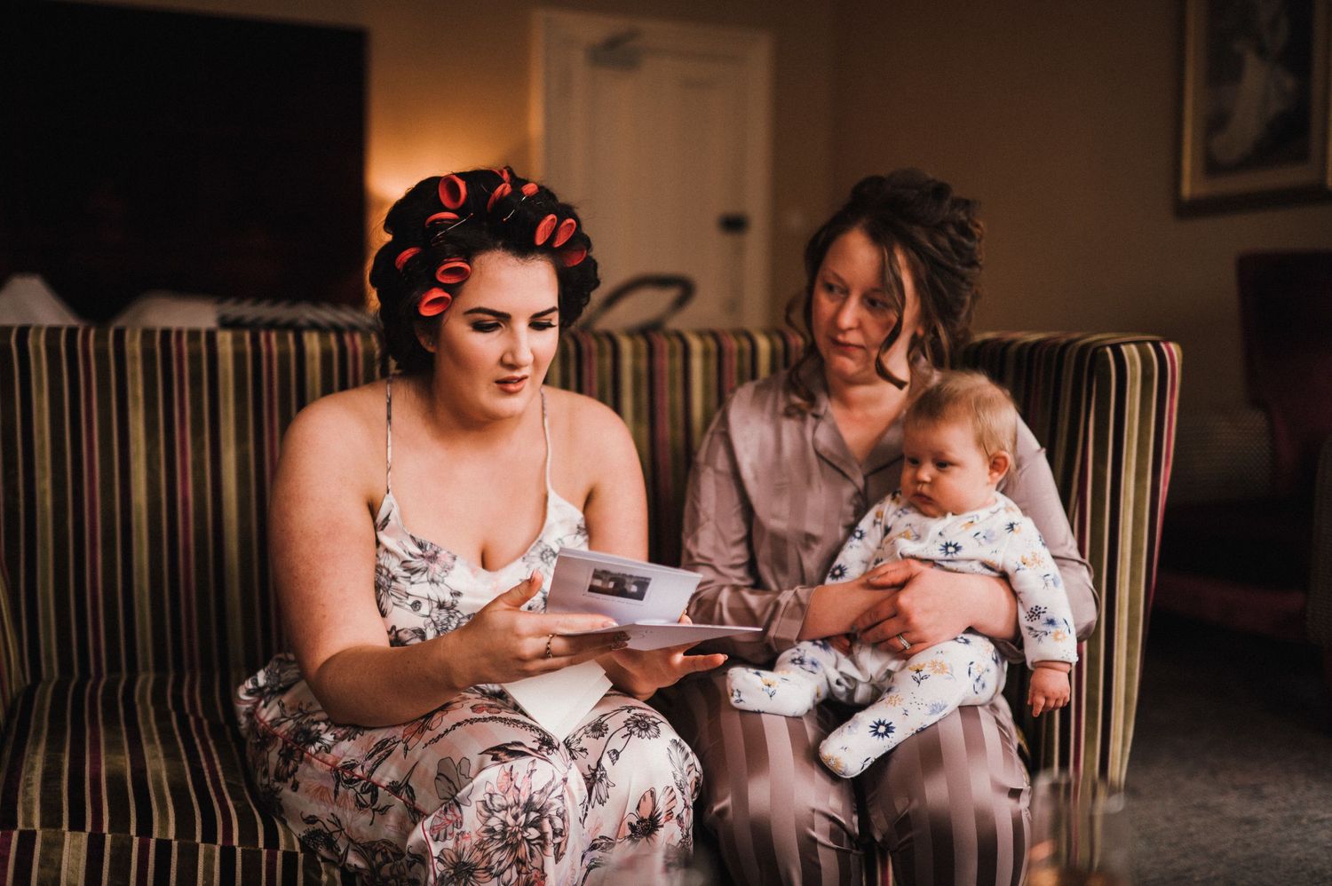 Family moment on striped couch looking at photo album together.