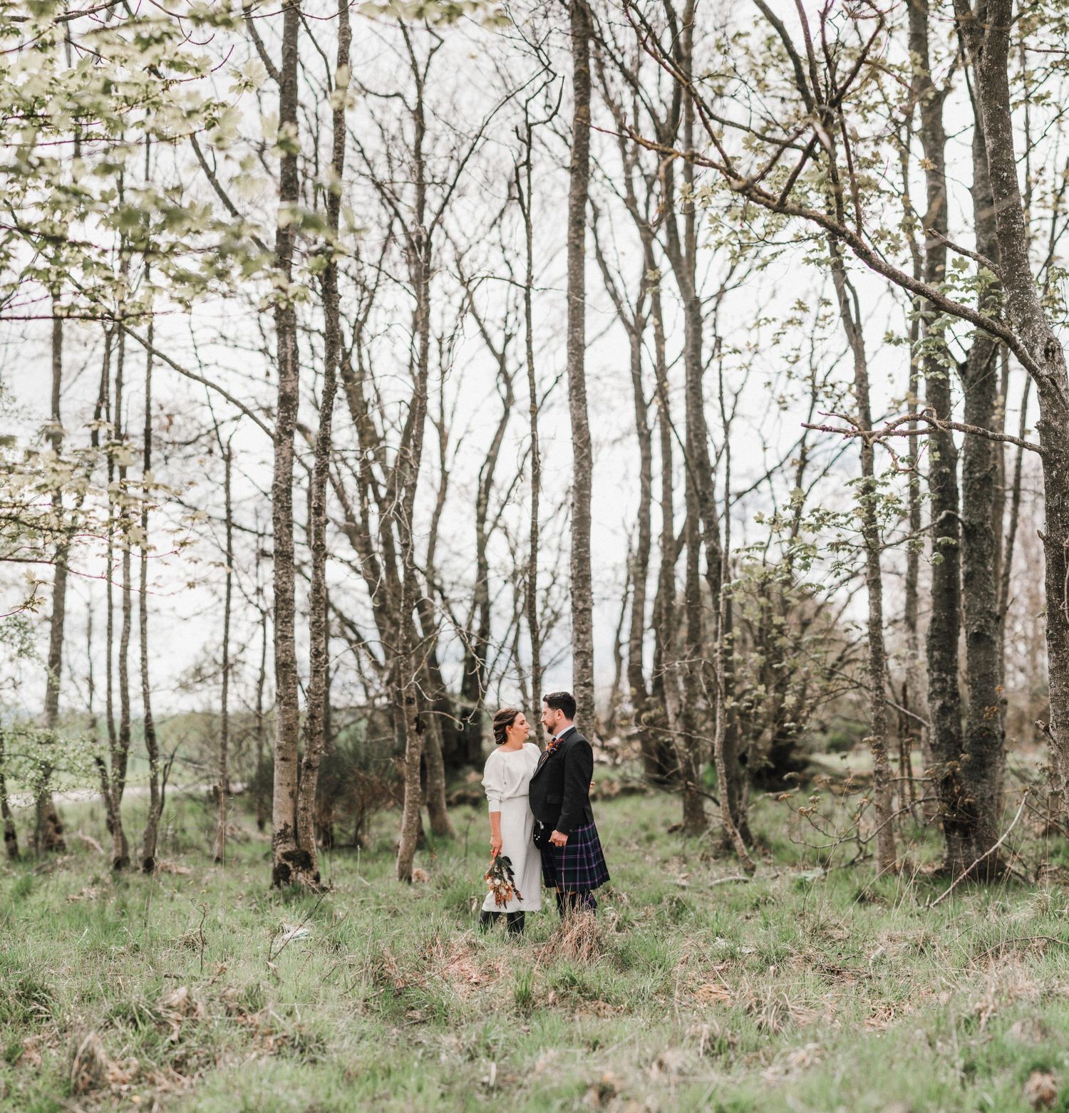 Newlyweds share an intimate moment in a serene wooded setting during spring.