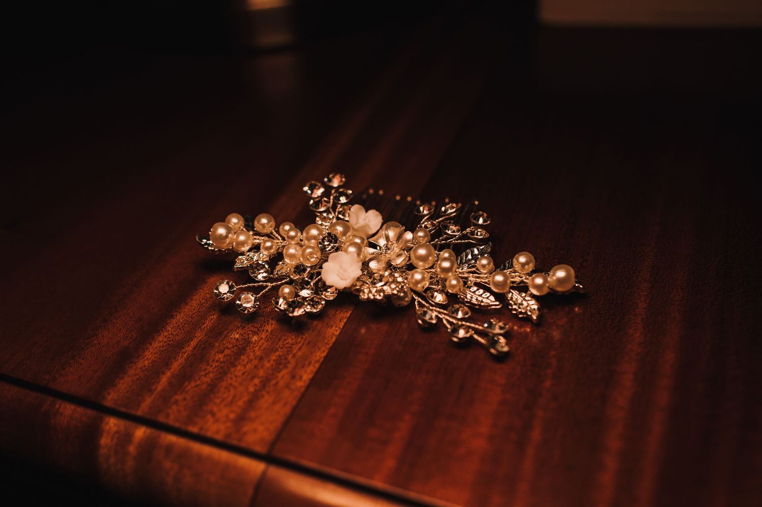 A delicate gold floral hair accessory for weddings on dark wooden surface.
