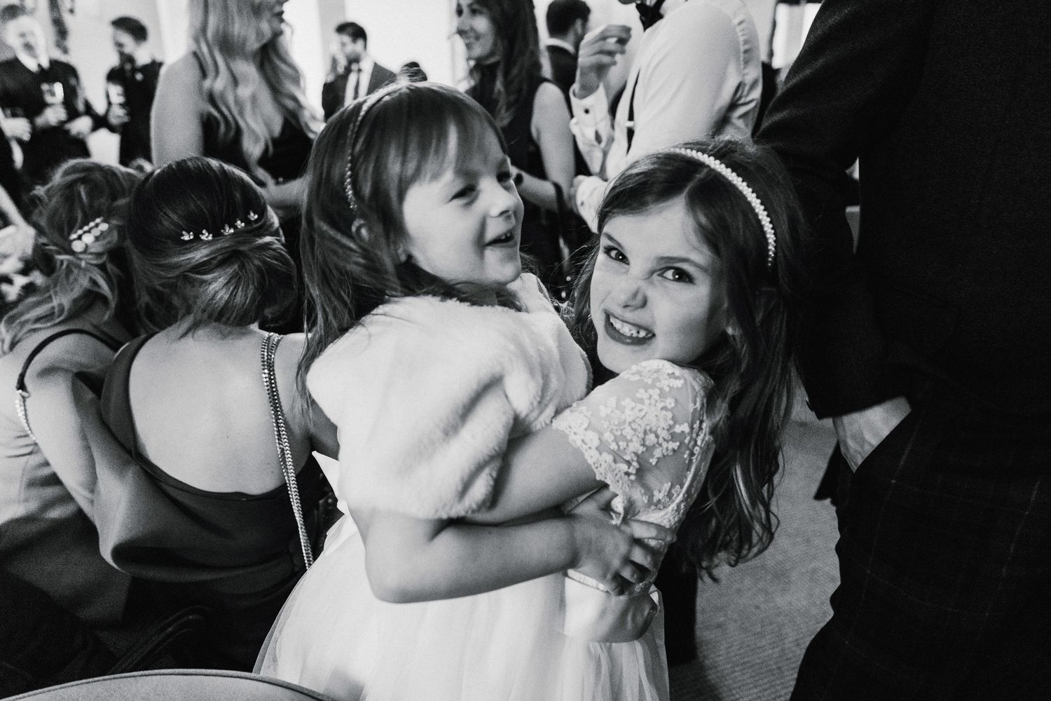 A black and white photo captures young attendees enjoying a festive moment at a wedding reception.