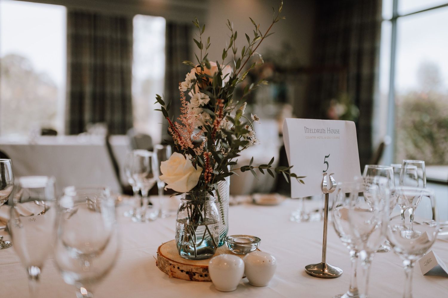 Wedding table setting with floral centerpiece, wine glasses, and place cards.