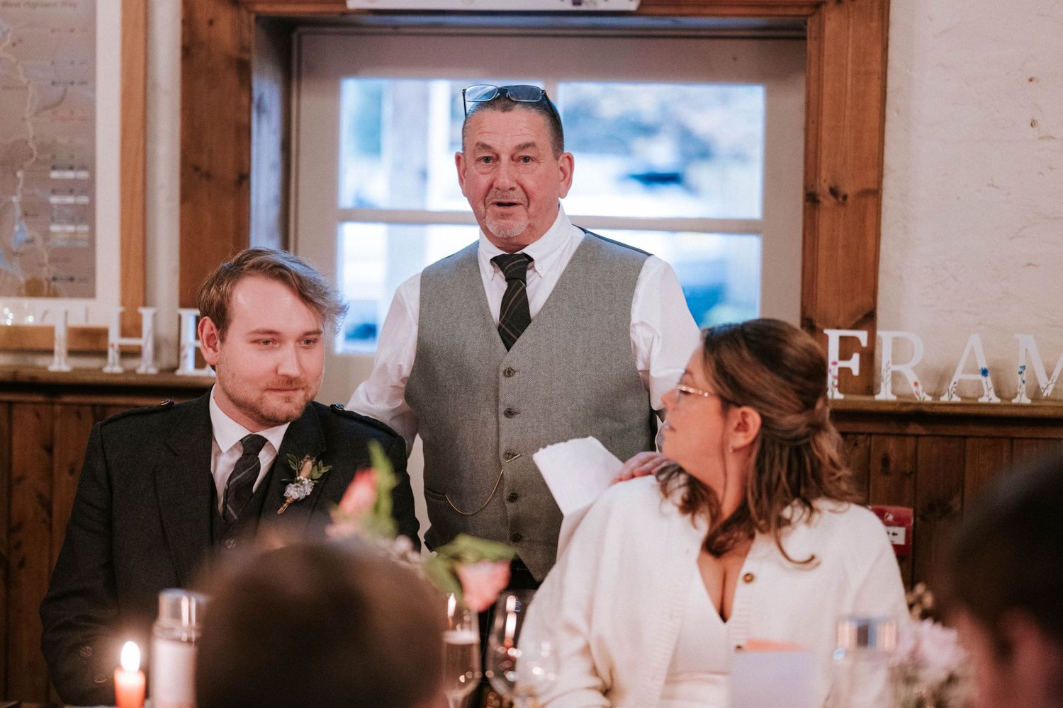 Wedding celebration in a rustic indoor venue with wooden beams and natural lighting.
