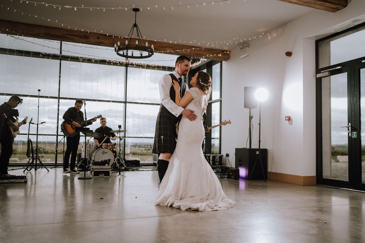 A couple shares their first dance in an elegant venue with a live band performing in the background.