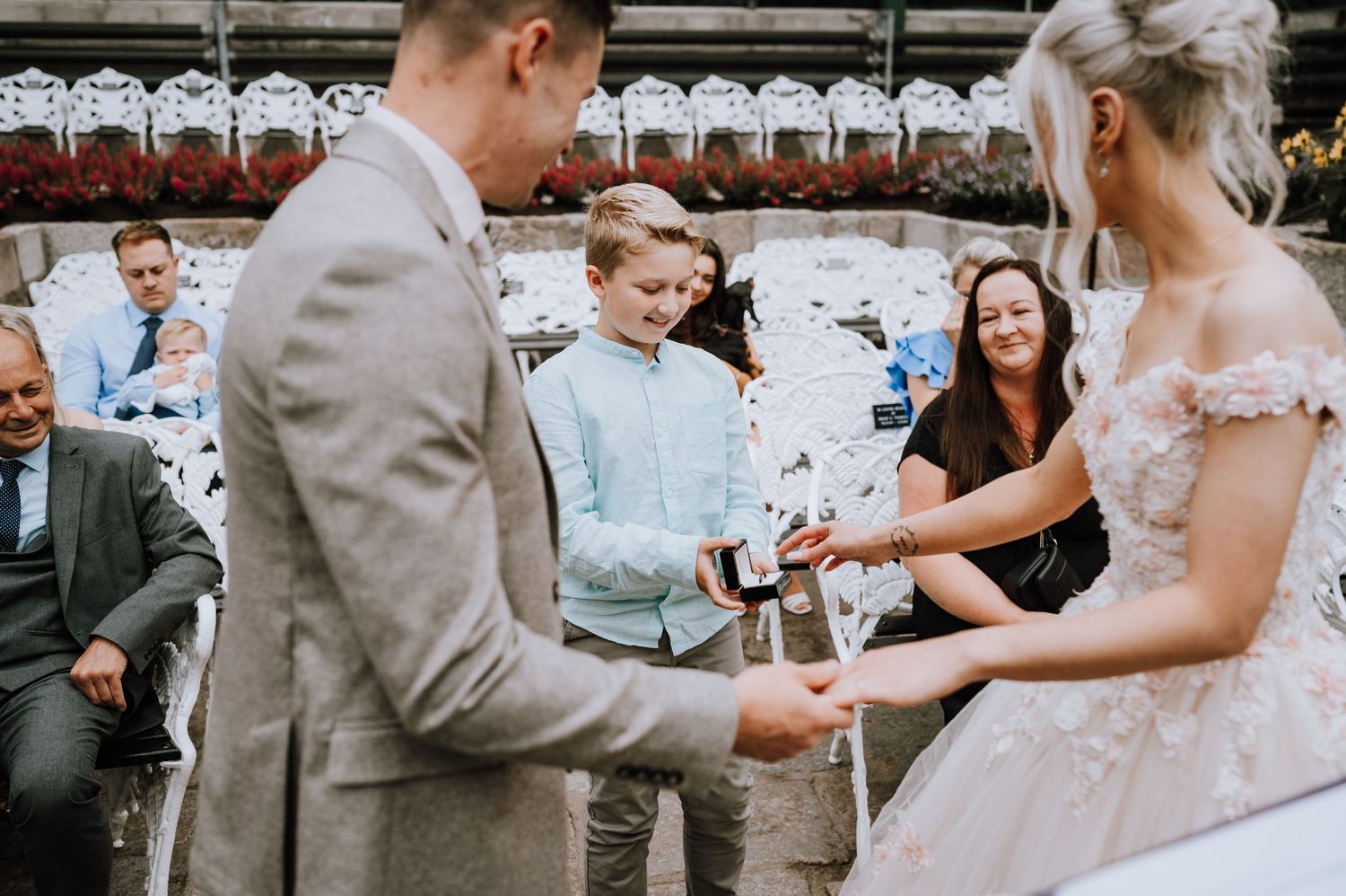 Ring exchange ceremony at an outdoor wedding with guests watching.