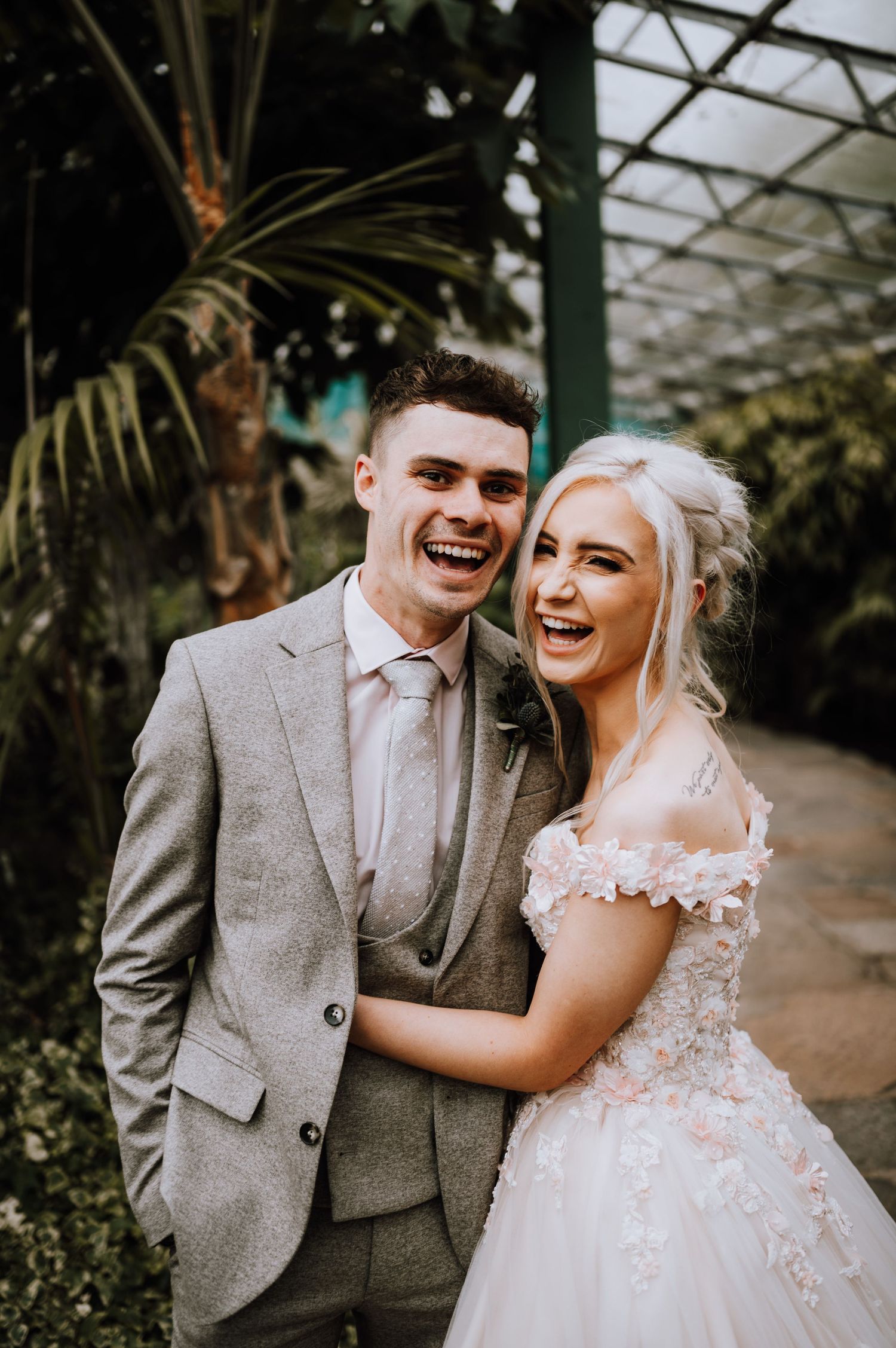 A joyful moment captured in a greenhouse wedding with natural light streaming through.