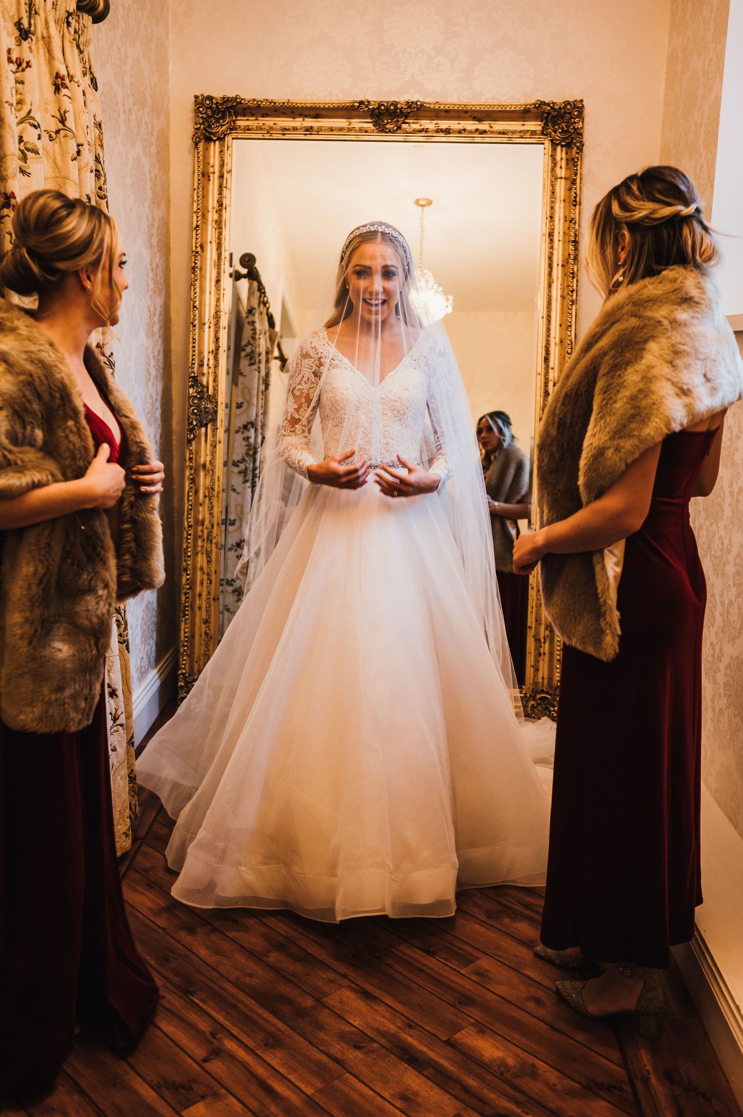 Aberdeen Wedding Photography. A bride in a stunning white ballgown being fitted in an elegant room with ornate gold mirrors.