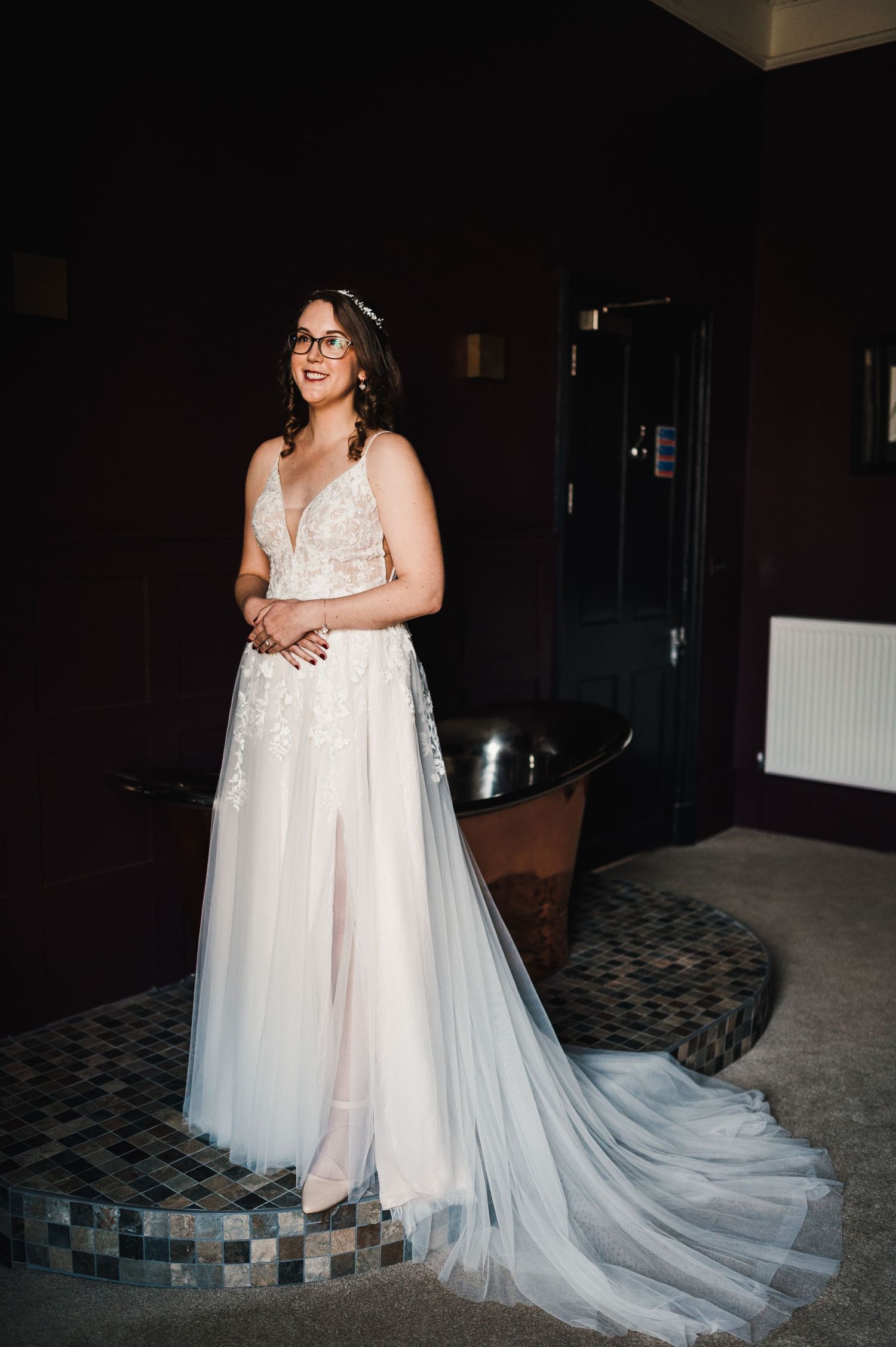 Aberdeen Wedding Photography. Bride in flowing white wedding gown with long train in dimly lit room.