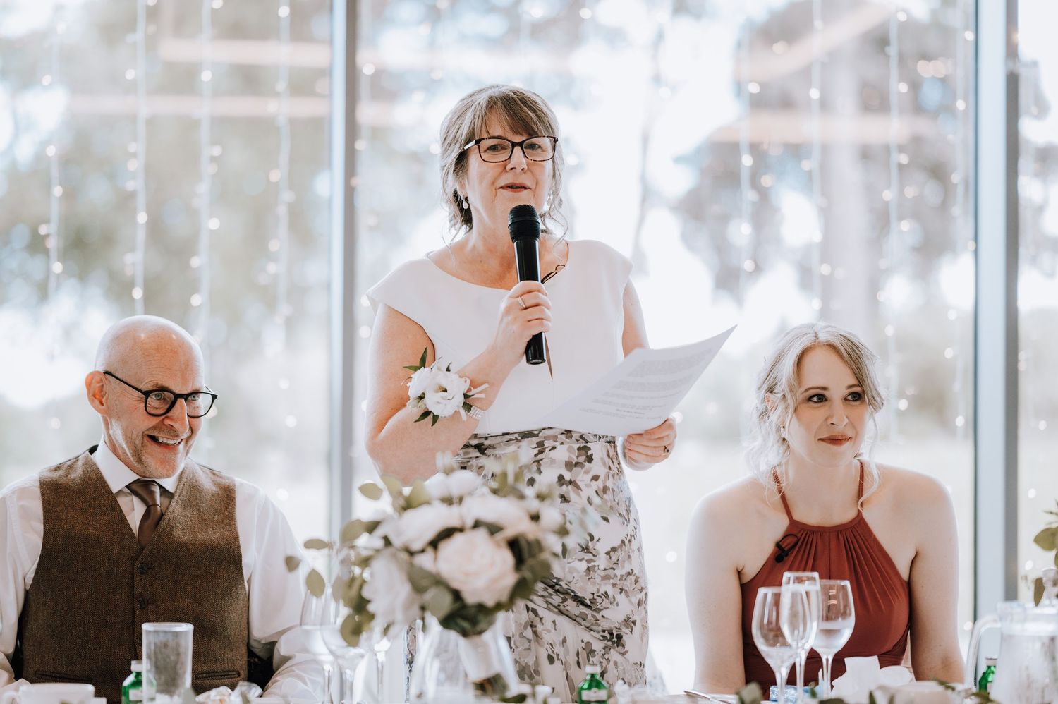 Wedding reception guests seated at decorated tables with floral centerpieces. Meldrum House Wedding Photography.