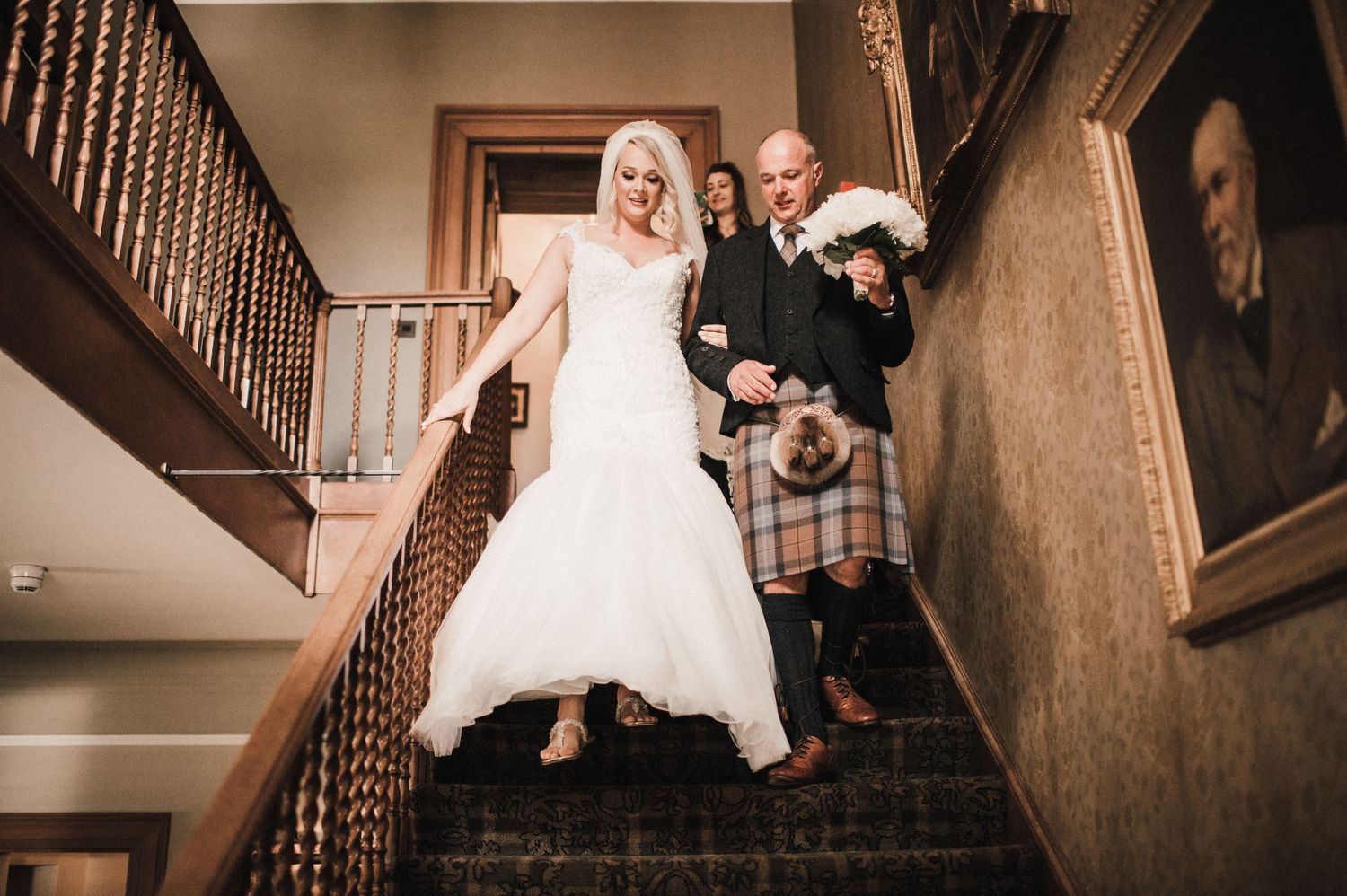 A couple descends an elegant staircase during their wedding celebration.