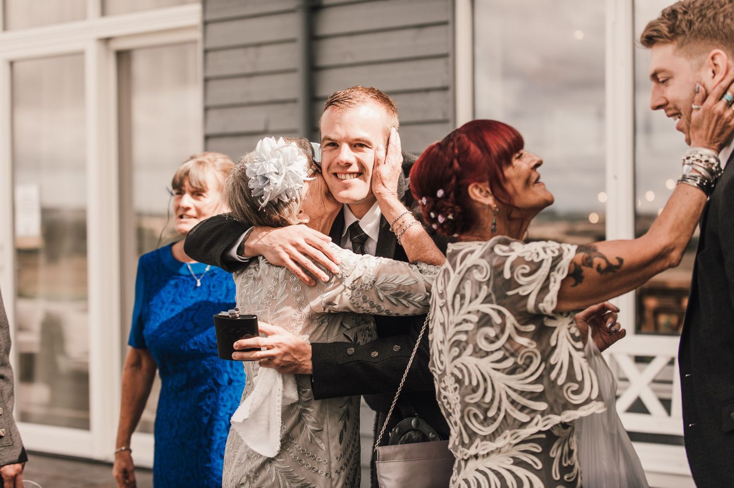 Joyful group hug shared among wedding guests during celebration.