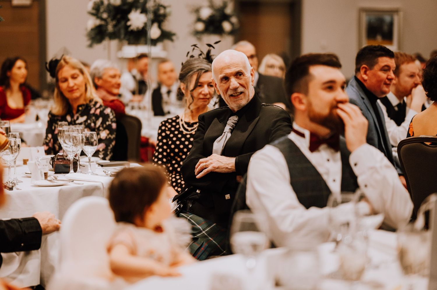 Wedding reception guests seated at round tables enjoying the festivities in an elegant venue.