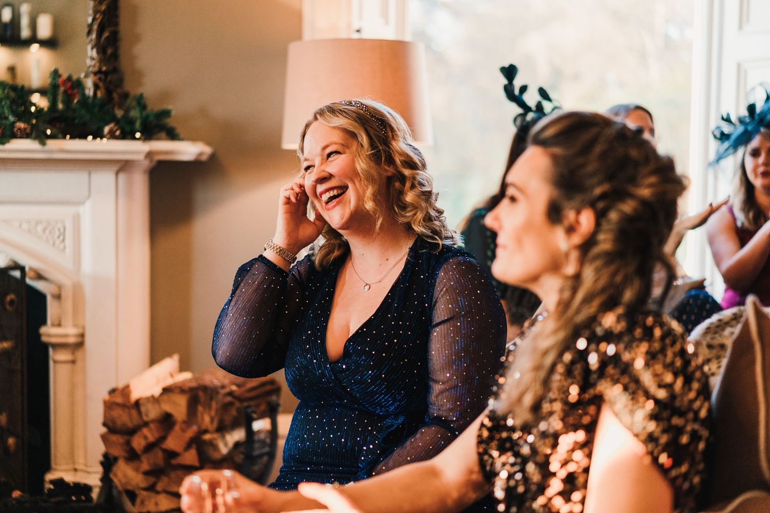 Joyful wedding guests laughing during indoor celebration with festive decorations.