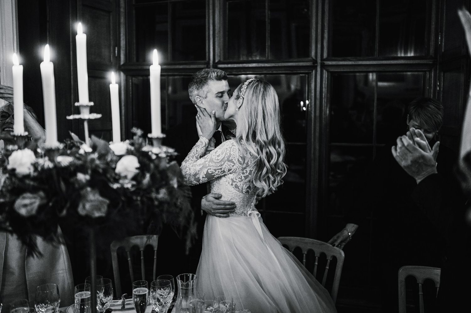 A romantic black and white wedding portrait with candlelight and floral arrangements.