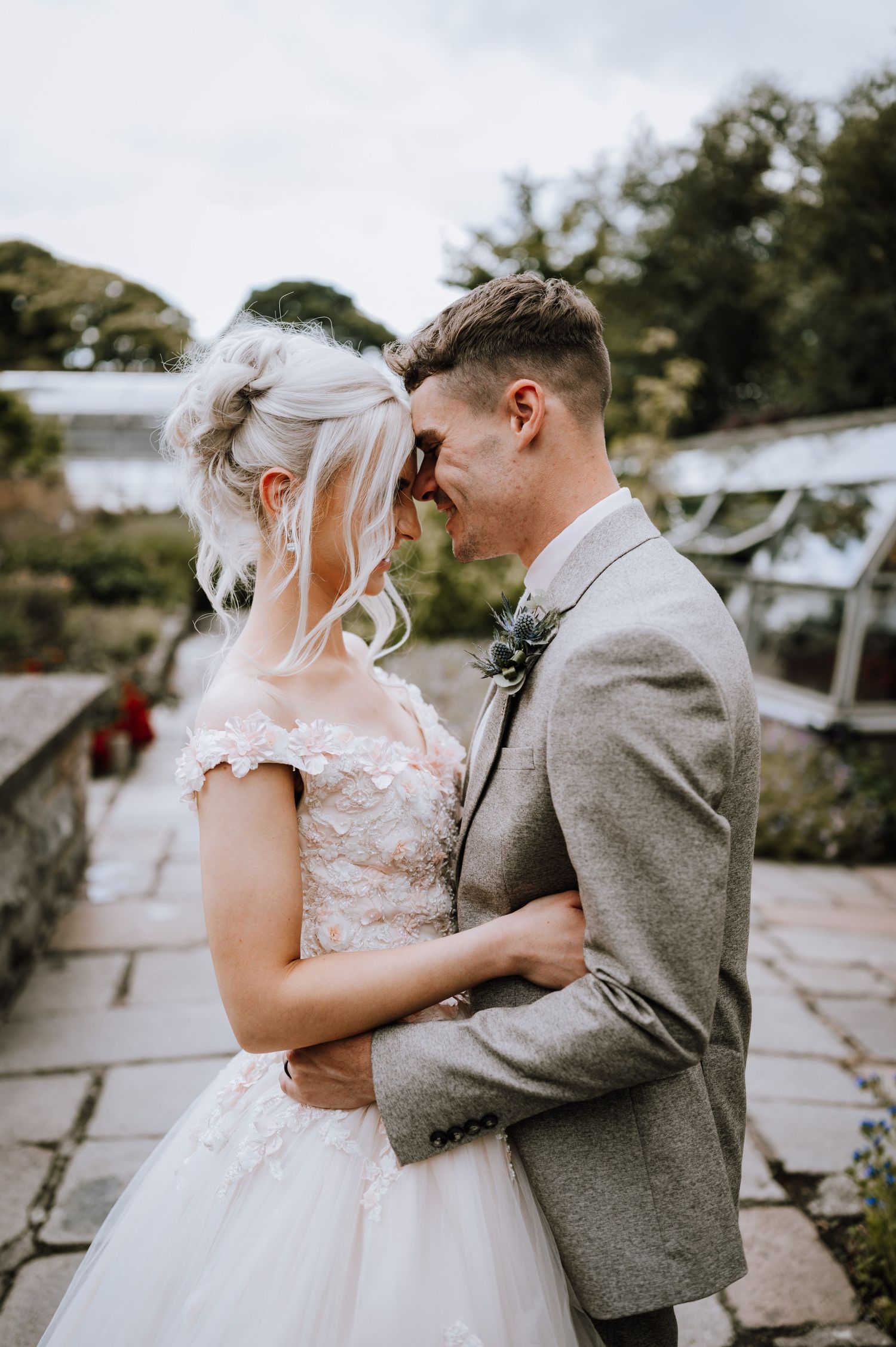 Newlyweds share an intimate embrace in a garden setting.