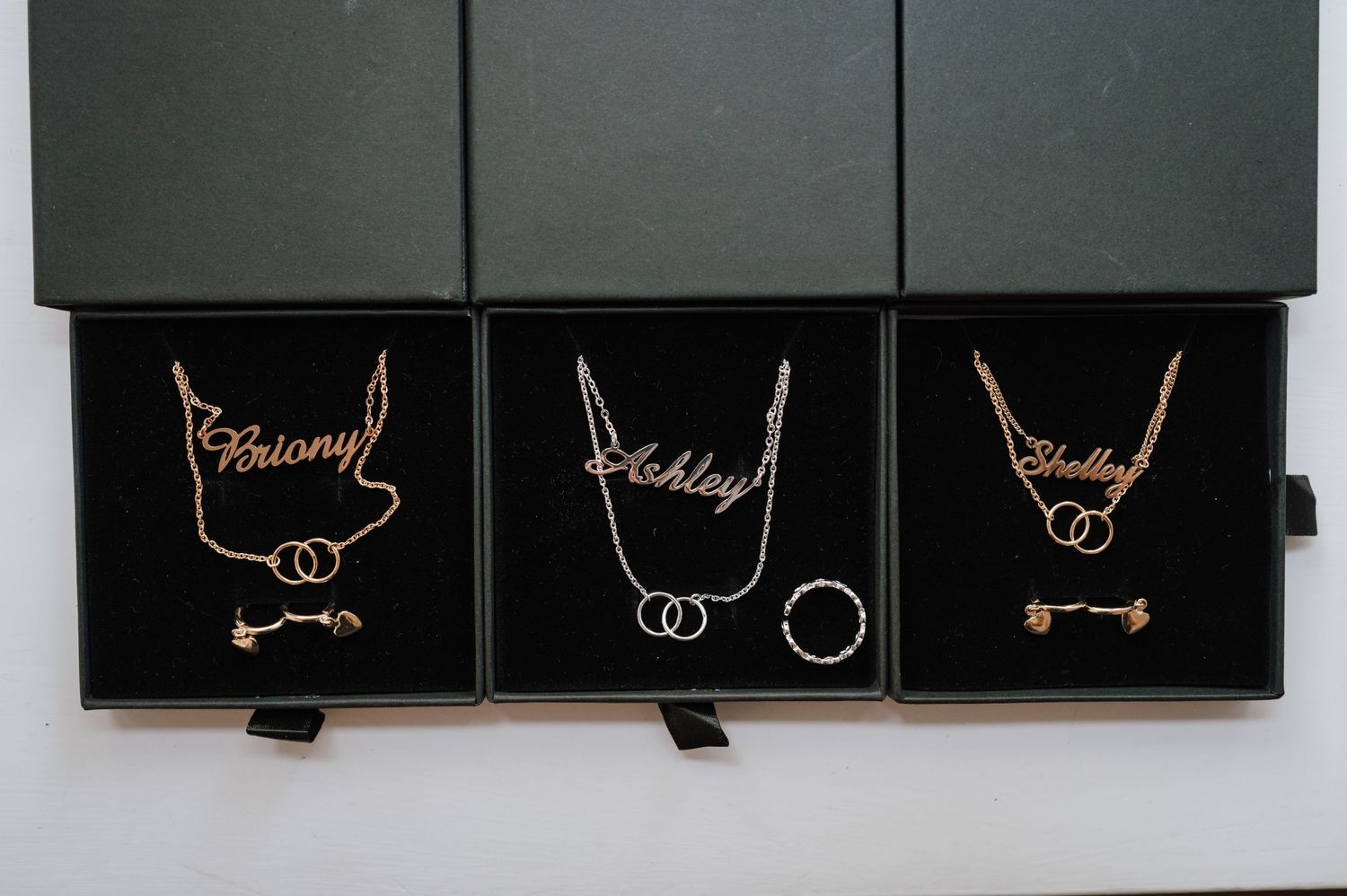 Three black framed artworks displaying delicate gold necklace designs with bone accents.