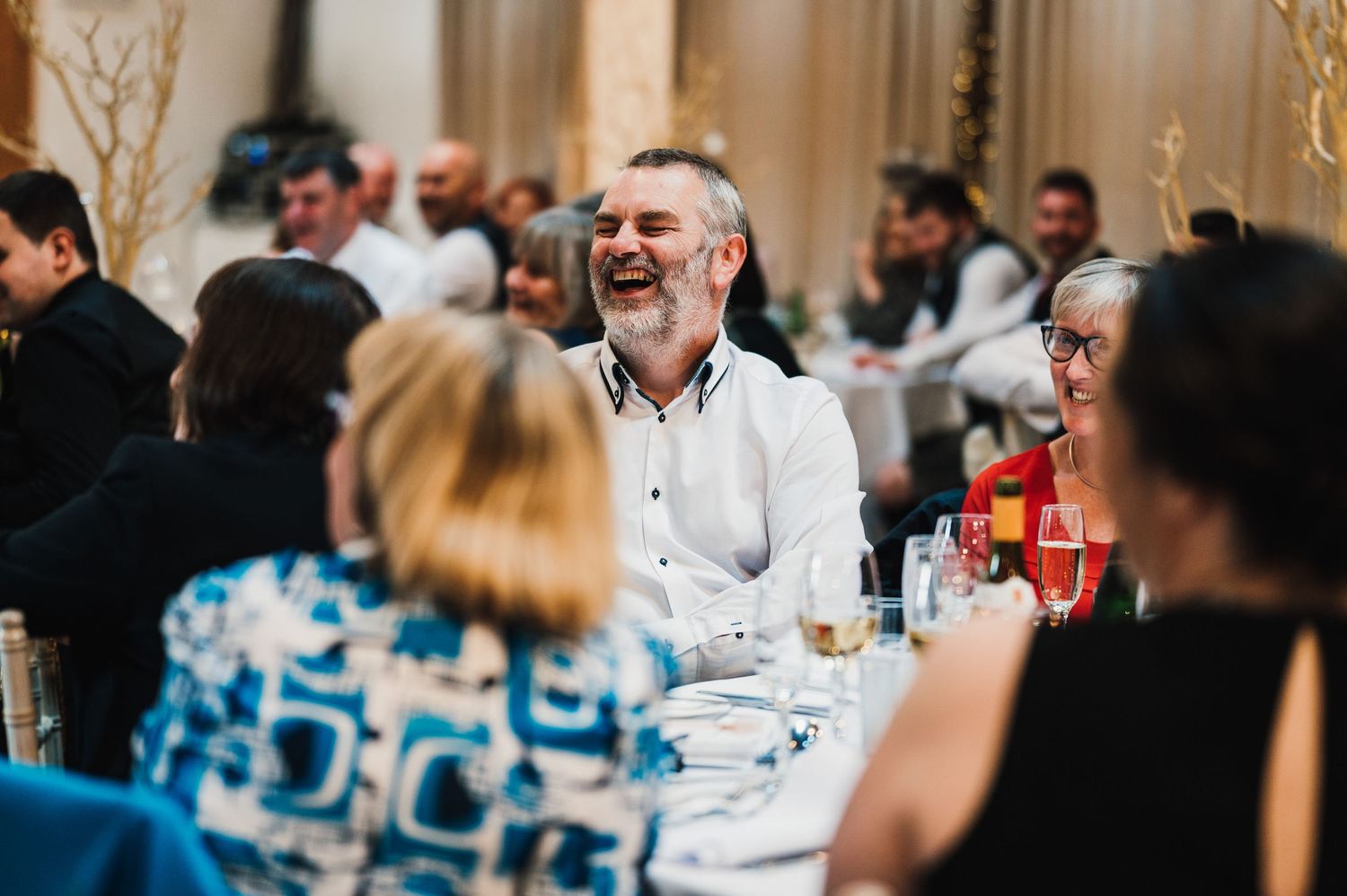 Joyful laughter shared during a festive dinner party with guests seated around tables.