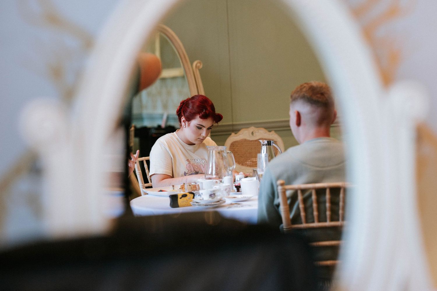Two people share a meal together at a restaurant table framed through an archway.