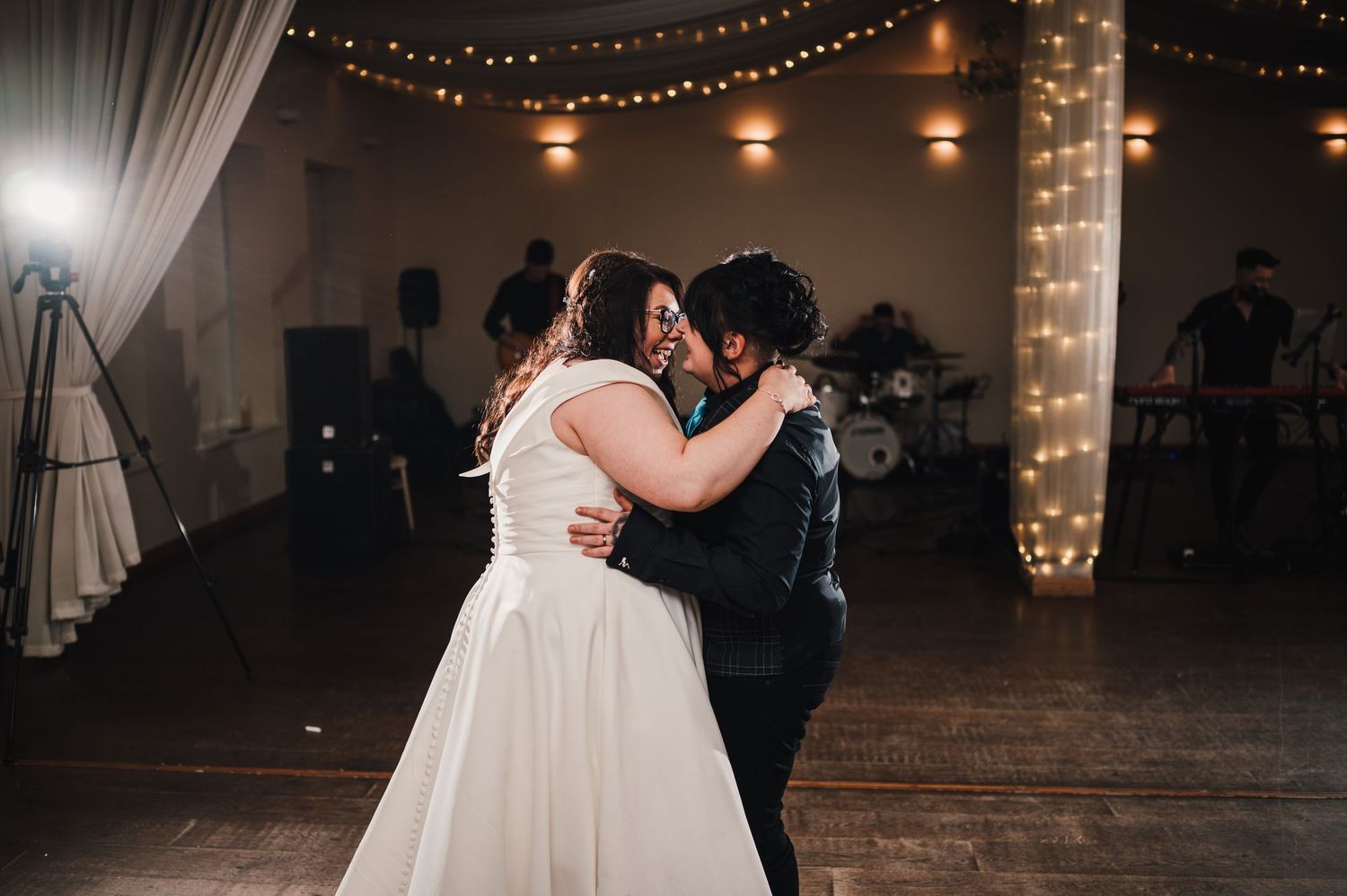 Logie House Wedding Photography. Wedding reception dance floor filled with guests under romantic string lights and white fabric draping.