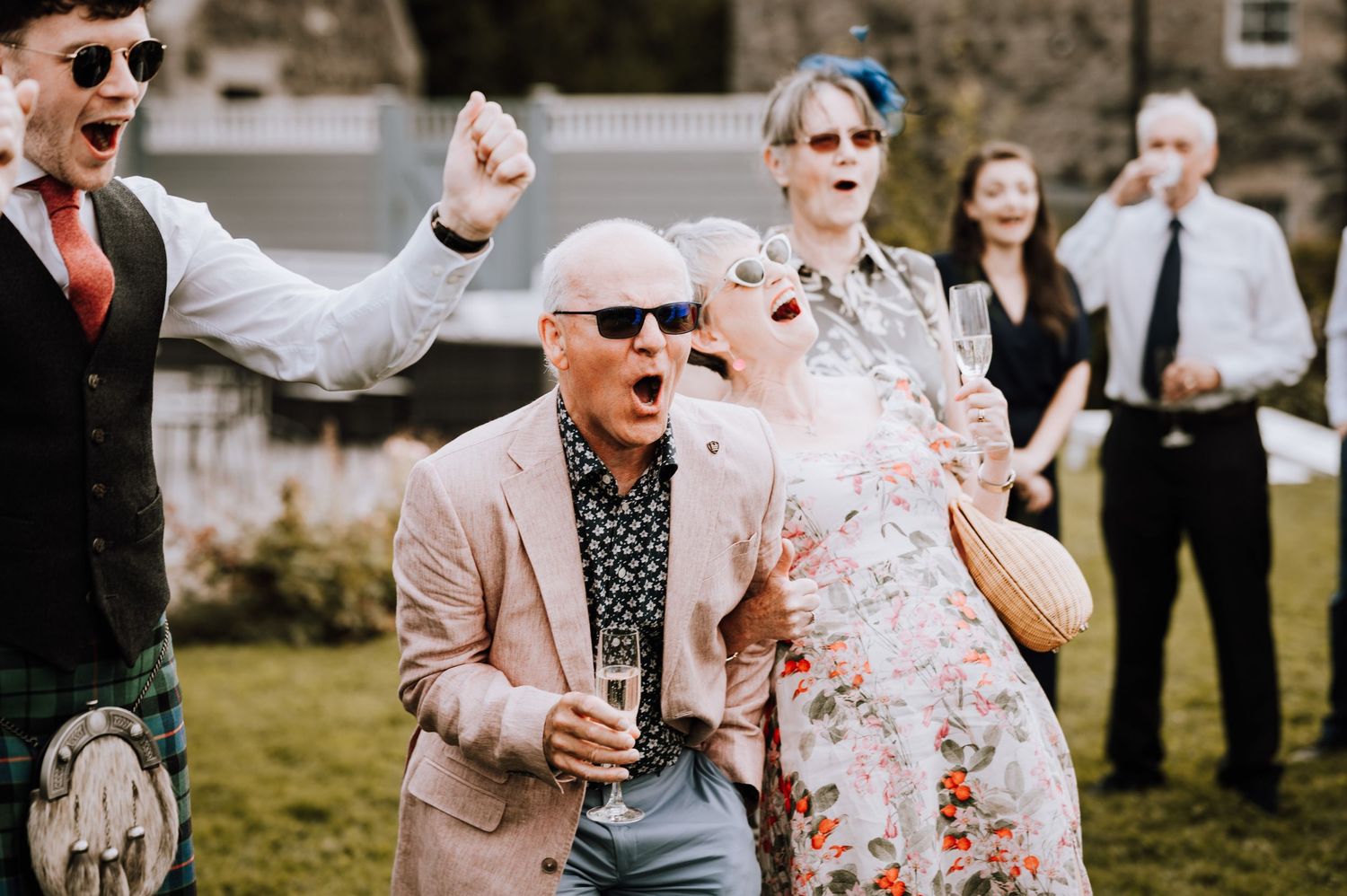 Aberdeen Wedding Photography. Wedding guests celebrate outdoors on a sunny day wearing sunglasses.
