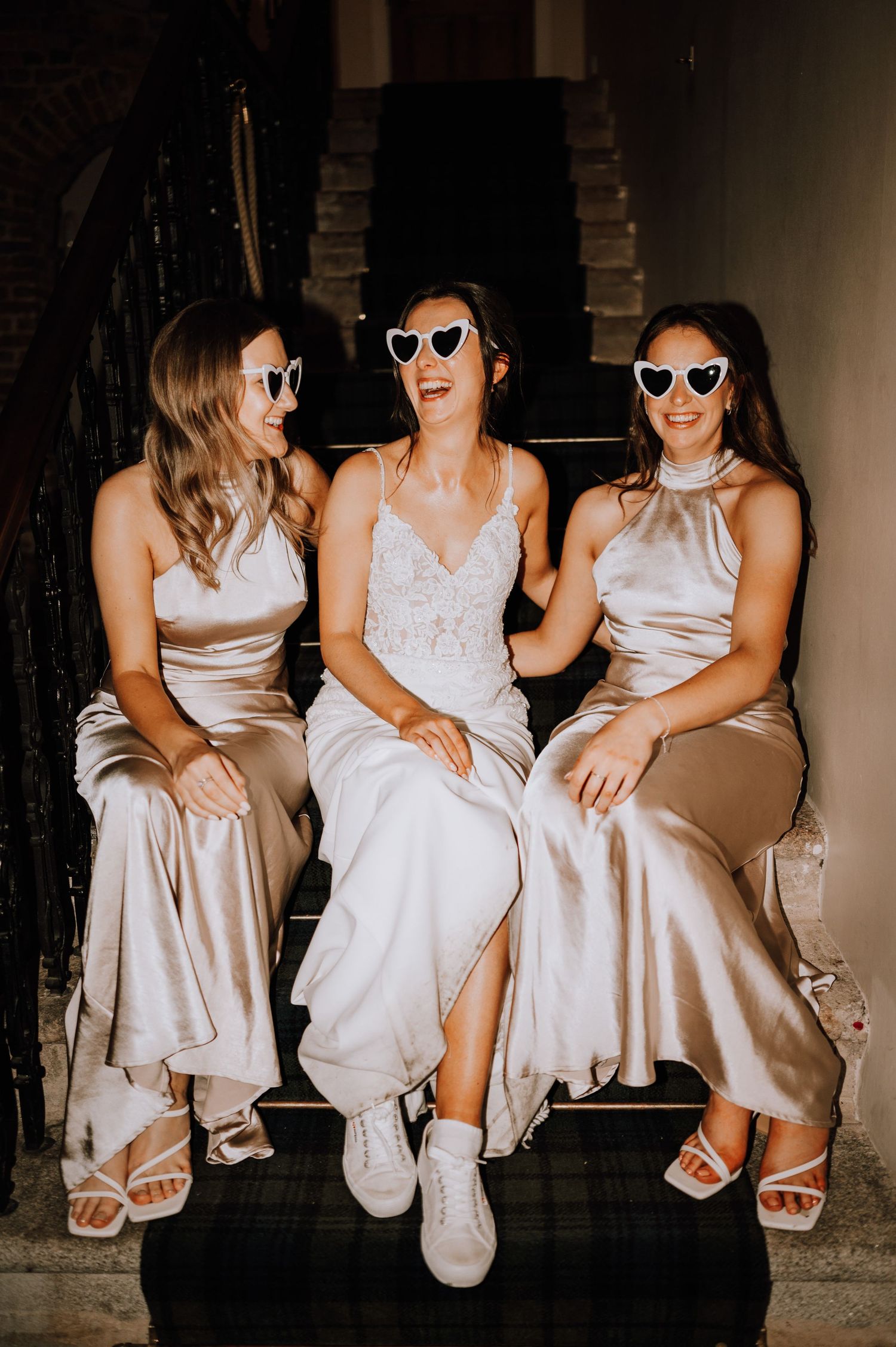 Aberdeen Wedding Photography. Three people in light-colored formal attire sit together wearing sunglasses indoors.