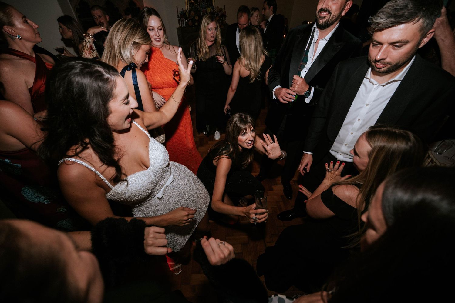 Wedding guests dancing and celebrating on a crowded dance floor at night.