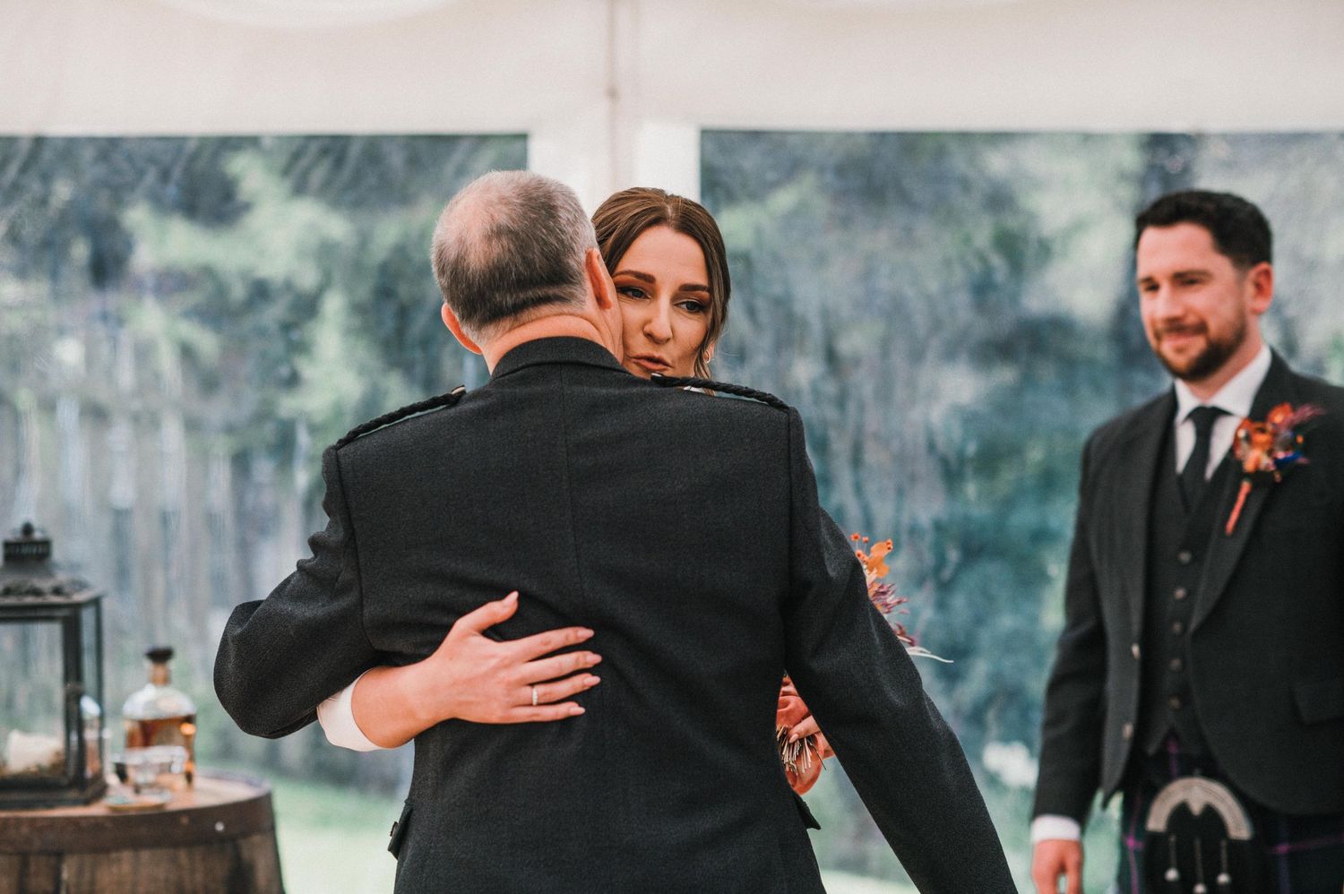A tender moment during a wedding ceremony with Scottish traditional elements under dim lighting.