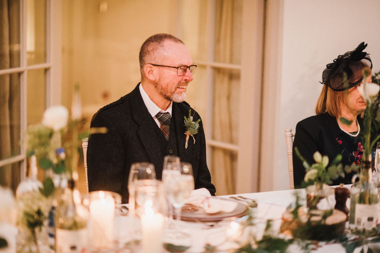 Guest seated at an elegant wedding reception table with candlelight and floral centerpieces.