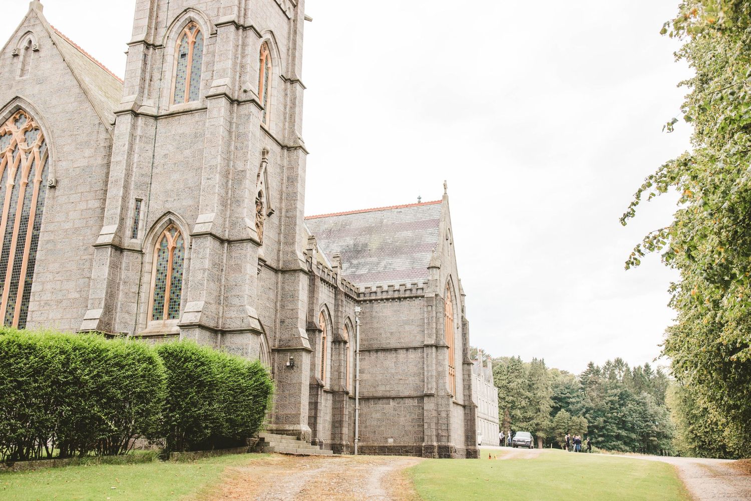 Gothic stone church exterior with tall spires and manicured grounds.