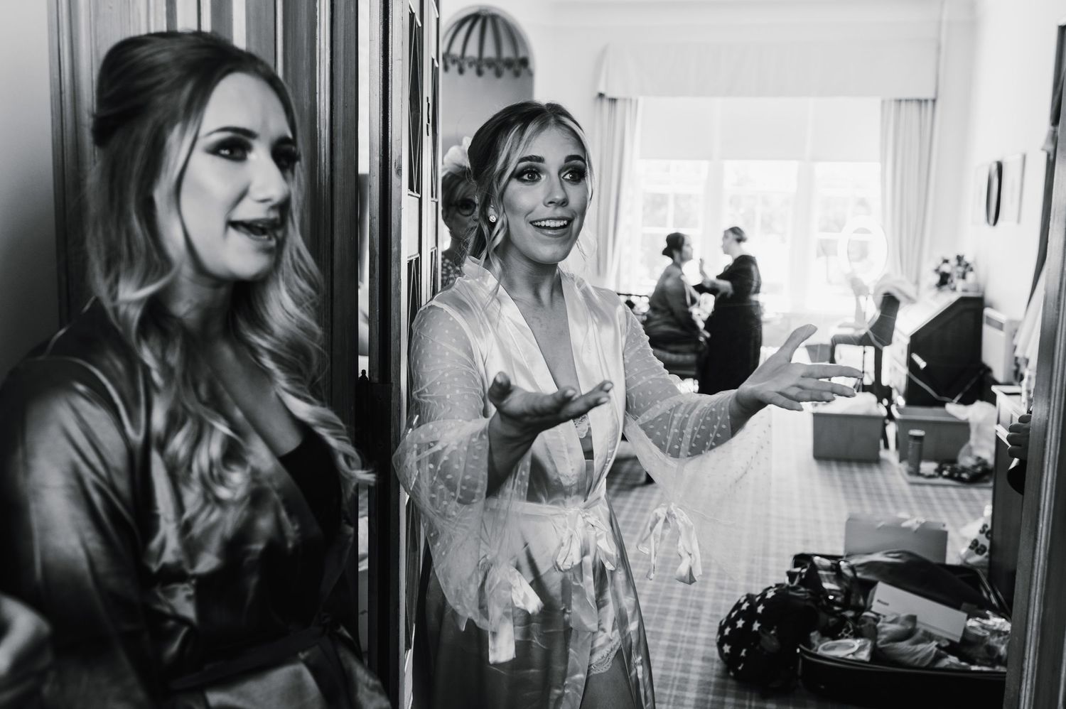 Black and white candid getting ready moment in window-lit room.