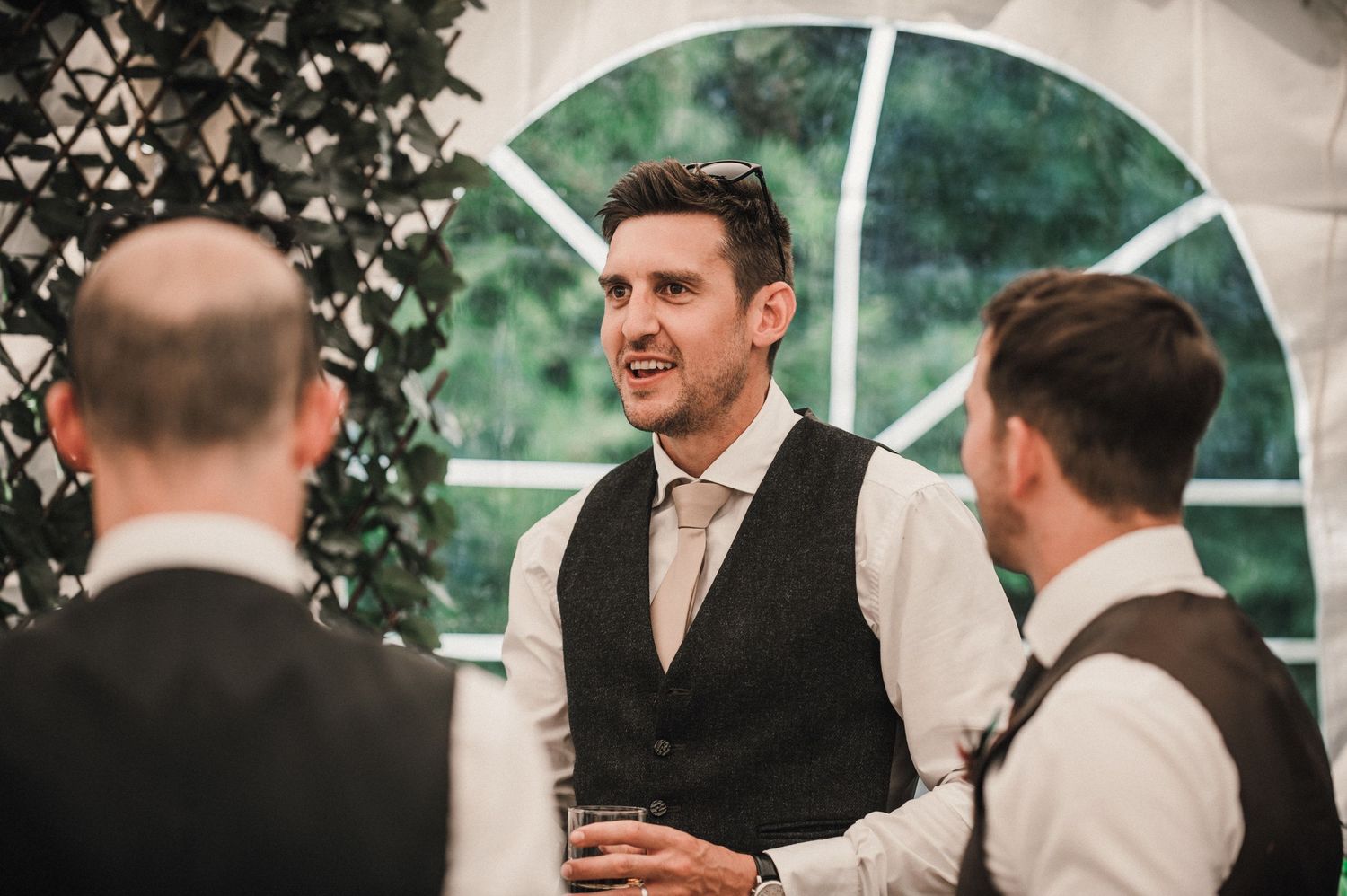 Wedding guests chatting and socializing in formal attire at an indoor venue.
