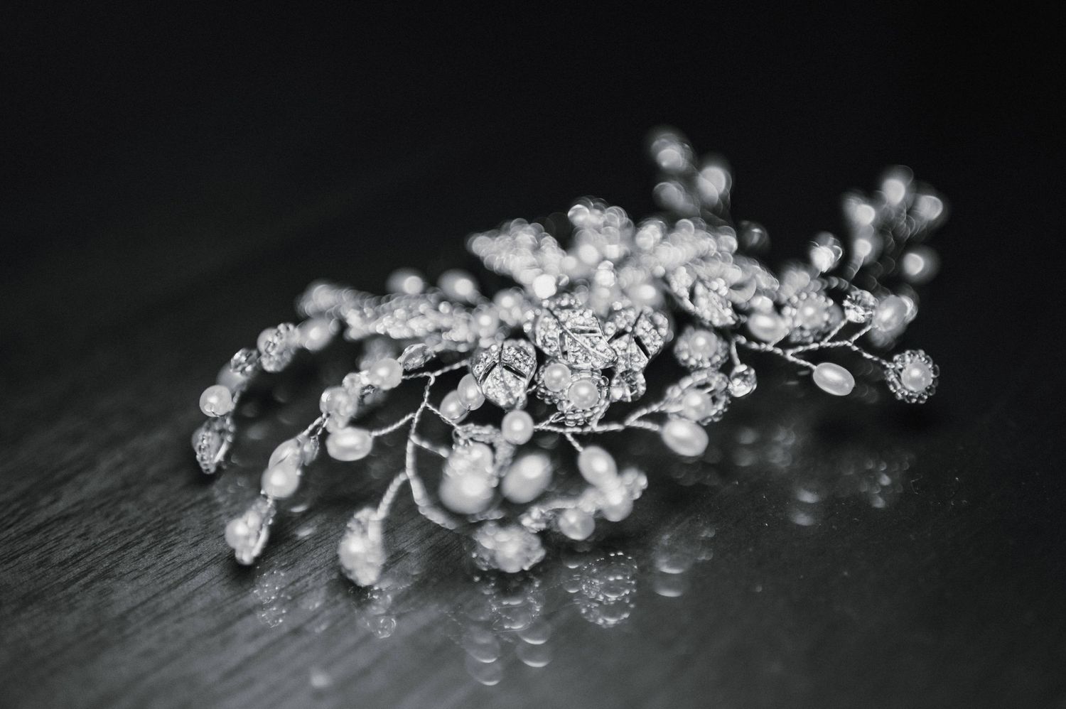 Delicate crystal hair accessory with pearl details on dark slate surface.