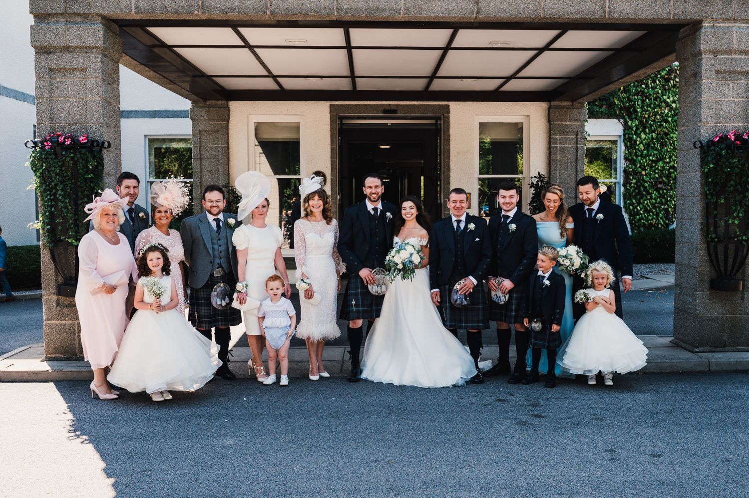 Wedding group photo featuring mixed generations in formal attire and Scottish kilts.